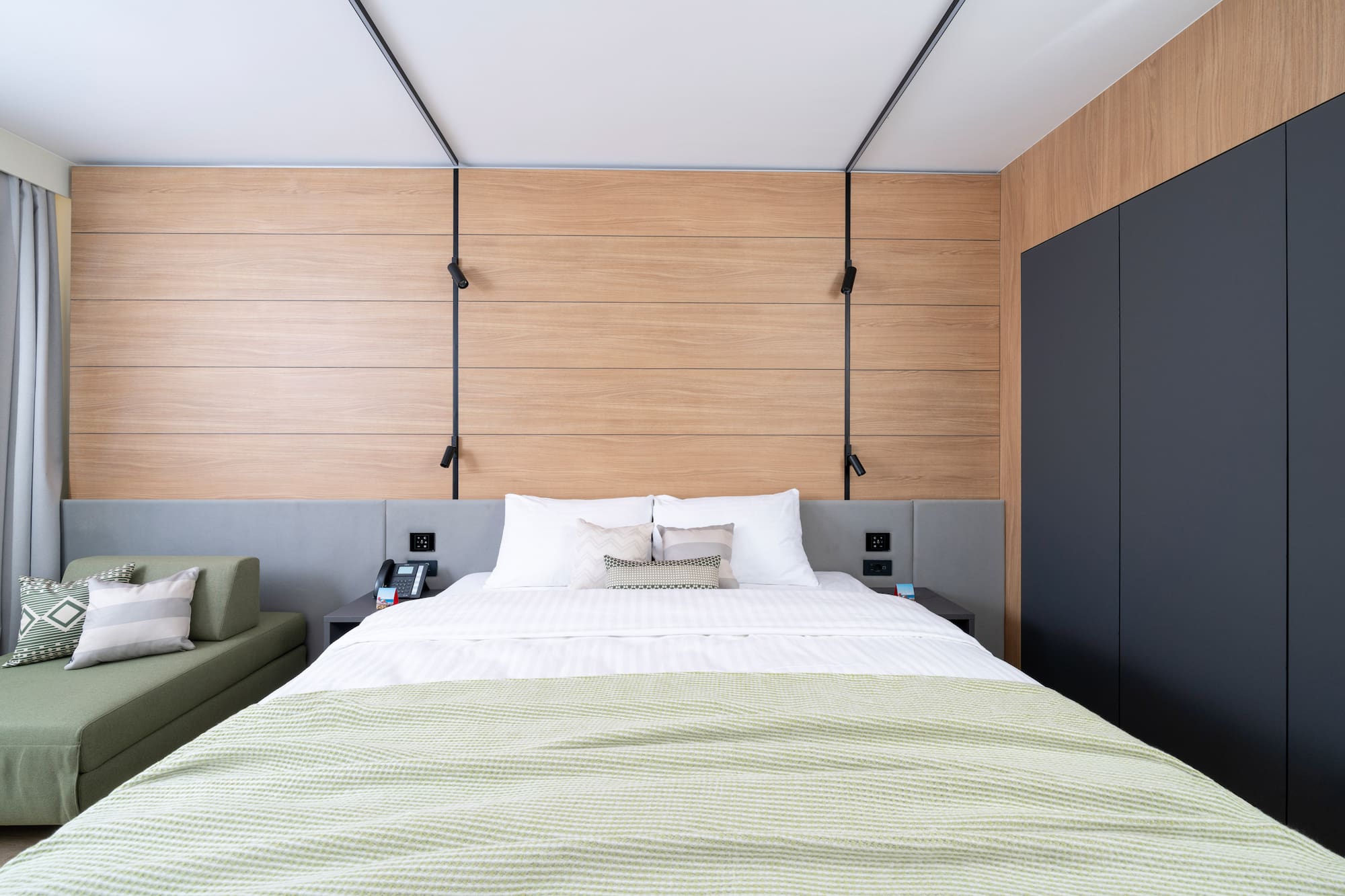 a bed with a green blanket and a black cabinet