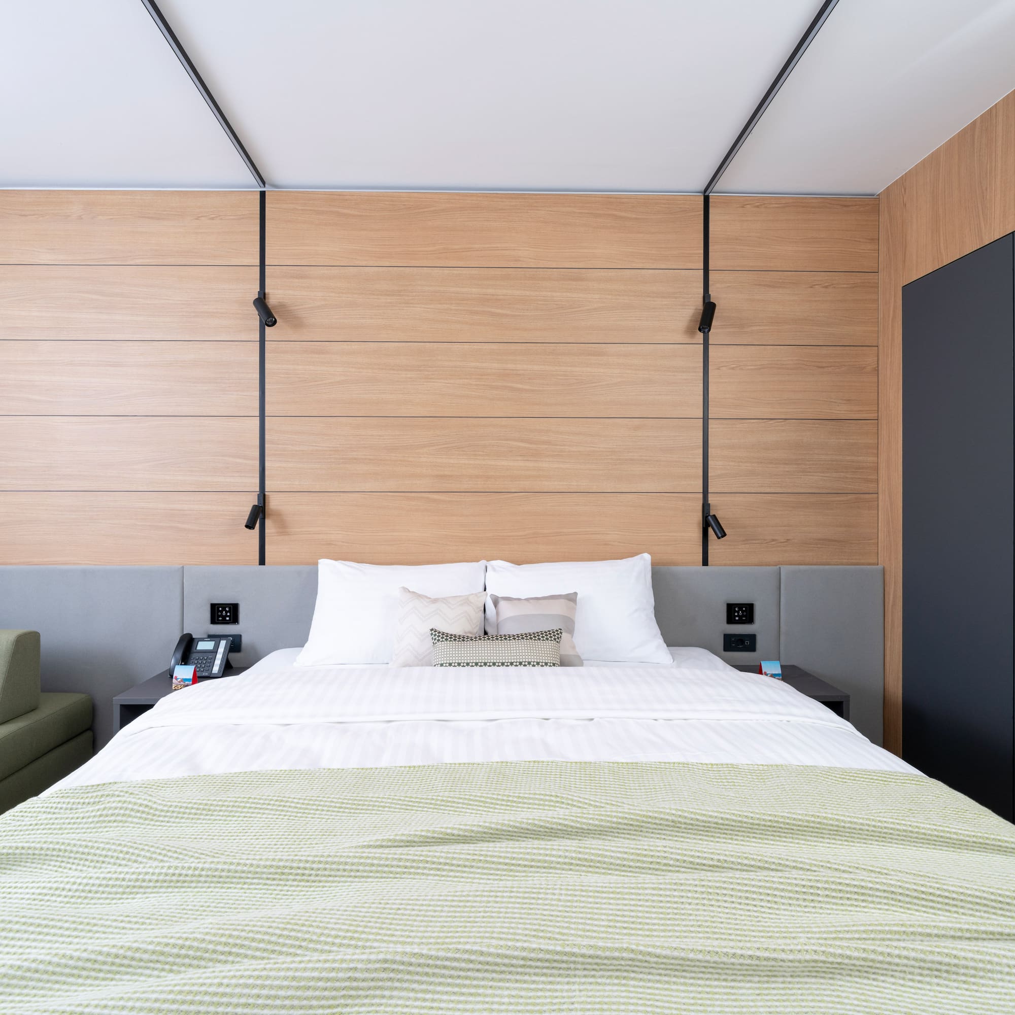 a bed with a green blanket and a black cabinet