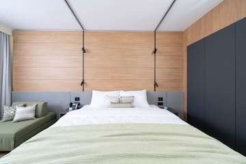 a bed with a green blanket and a black cabinet