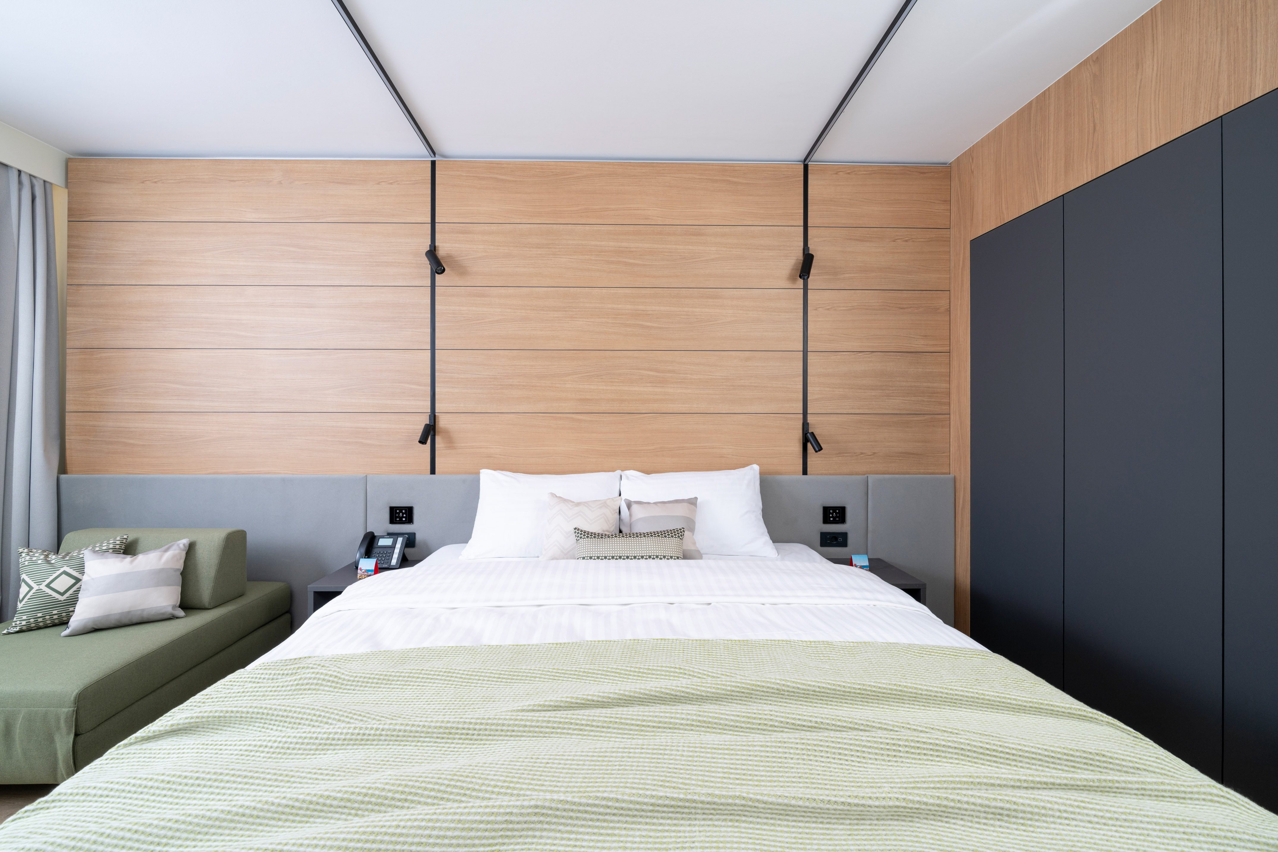 a bed with a green blanket and a black cabinet