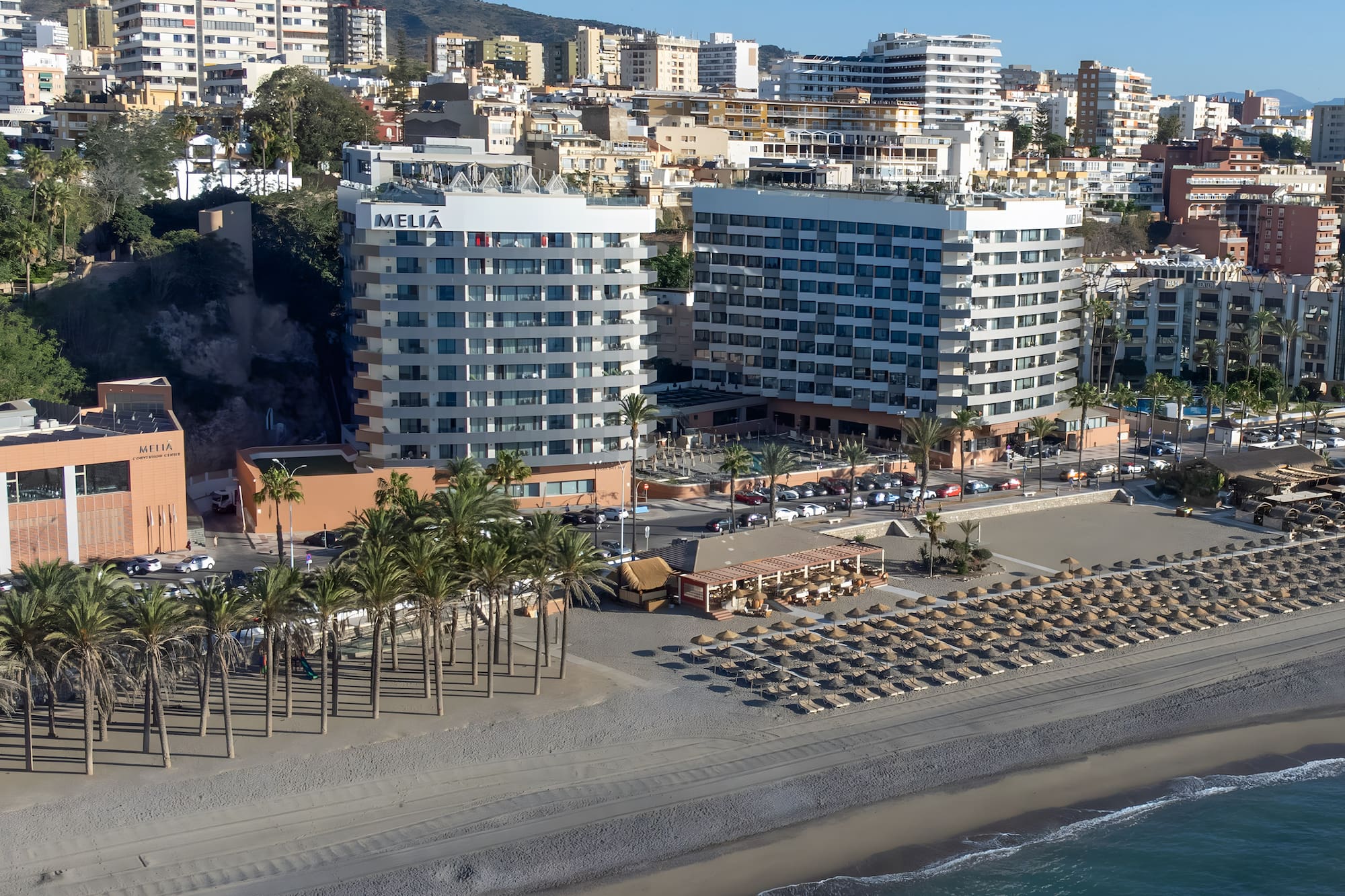a beach with many buildings and palm trees