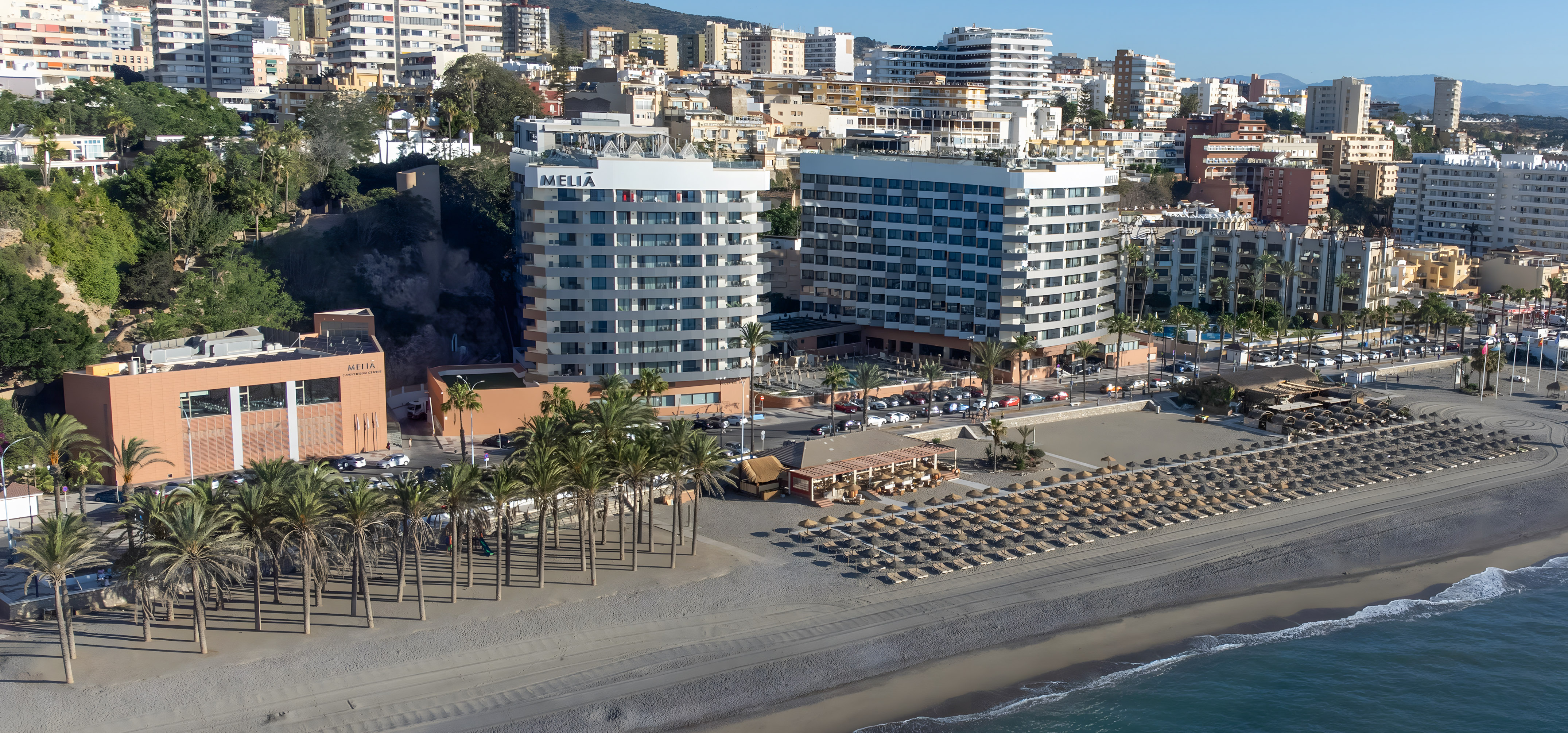 a beach with many buildings and palm trees