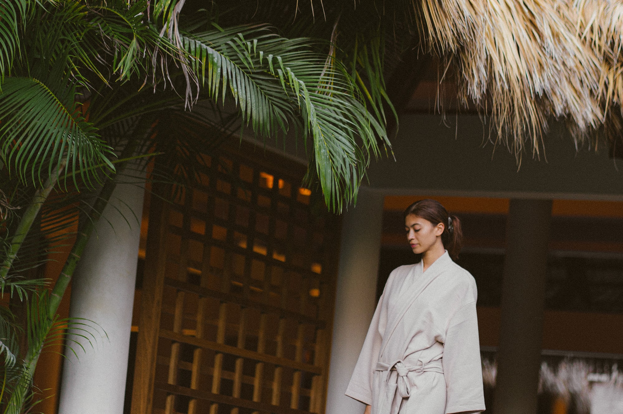 a woman standing under a palm tree