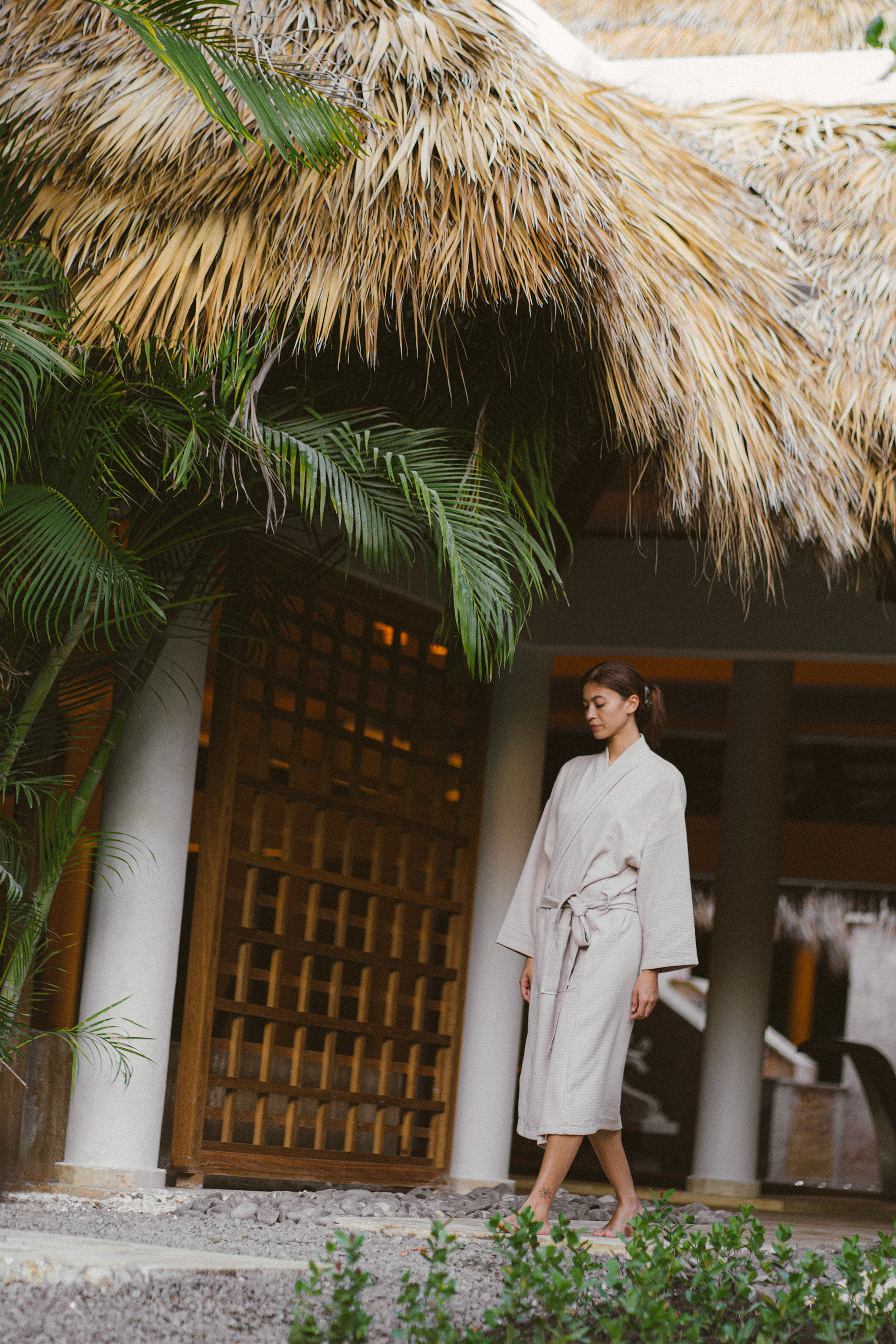 a woman standing under a palm tree
