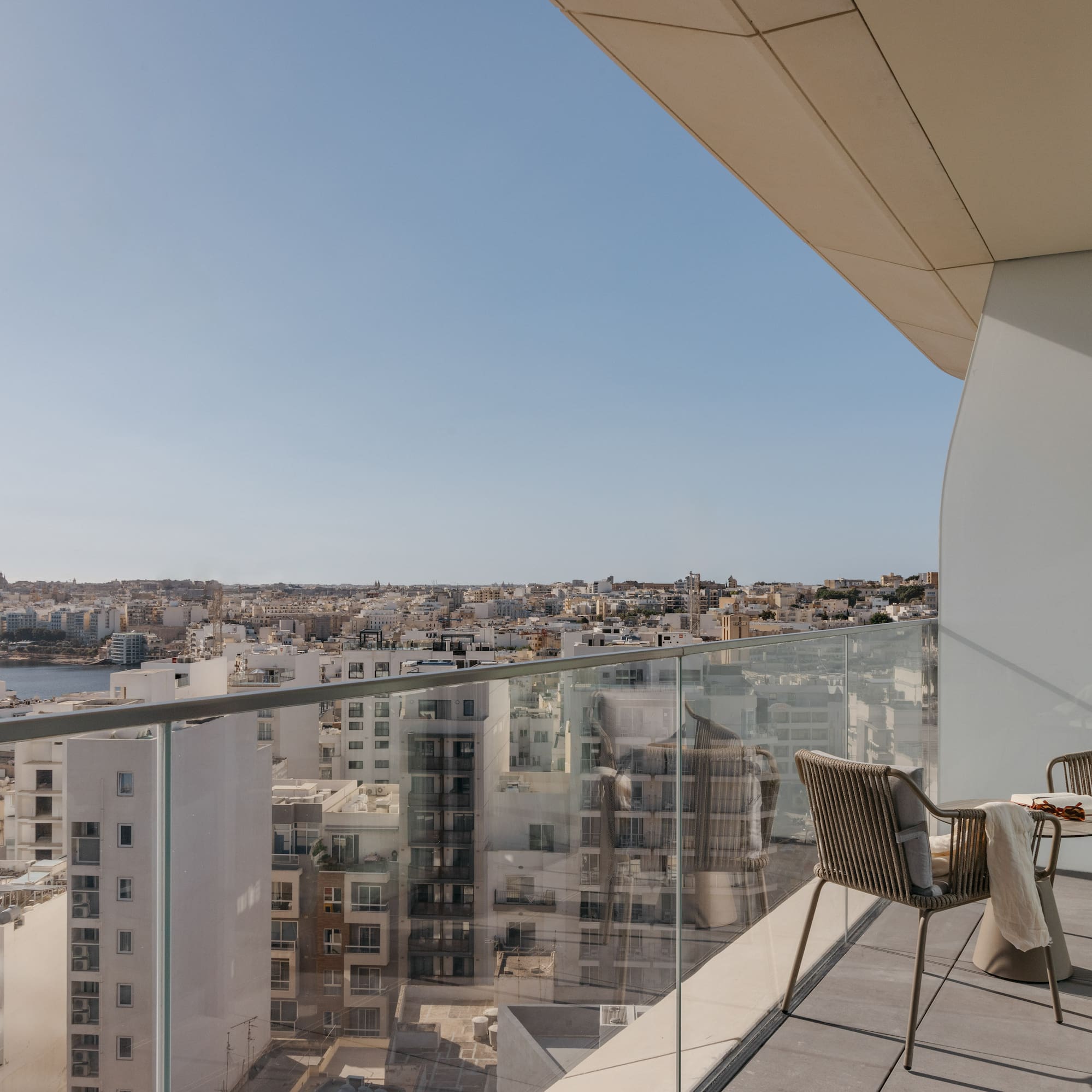 a chair and table on a balcony overlooking a city