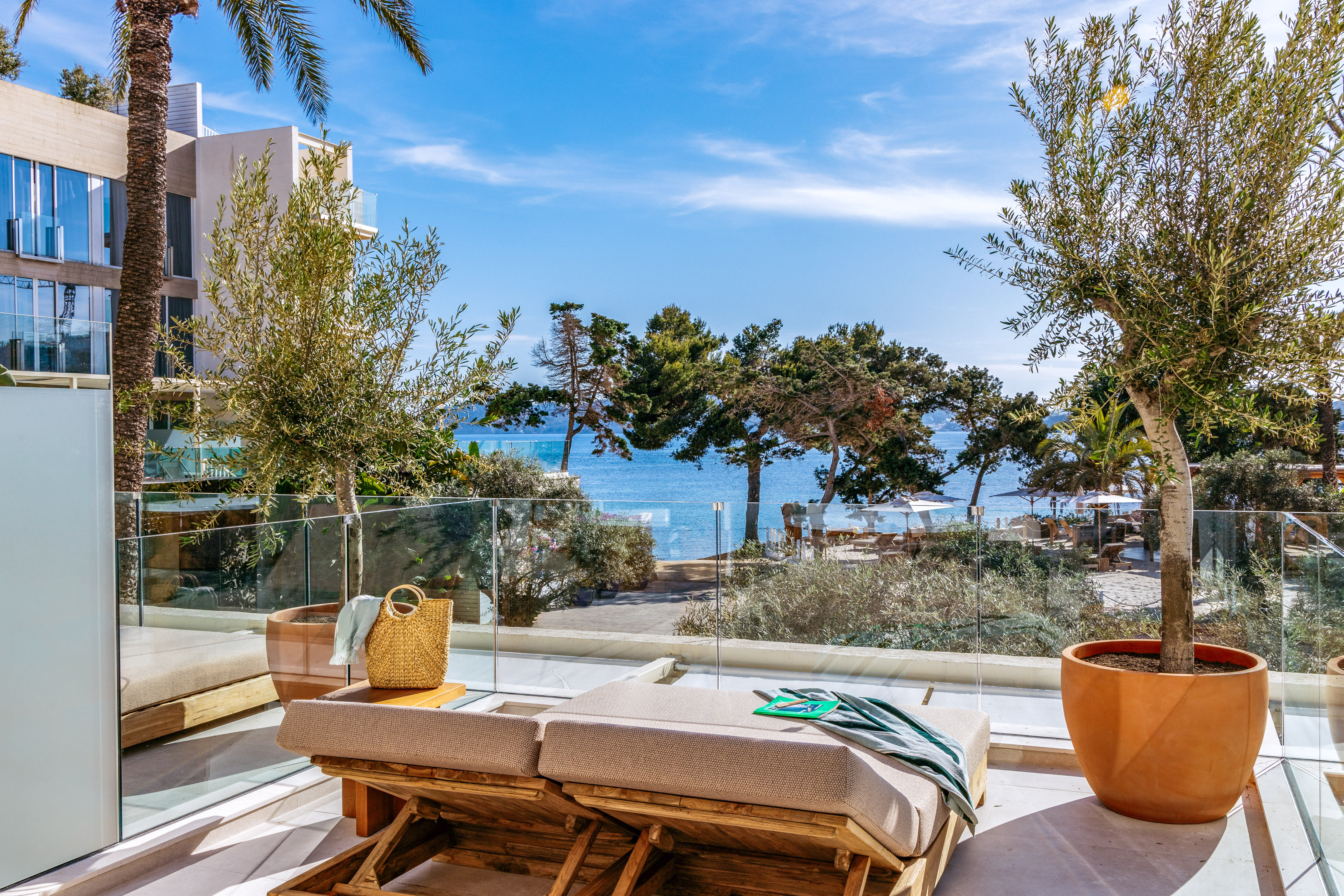 Sunny Mediterranean resort balcony with sea view, sun loungers.