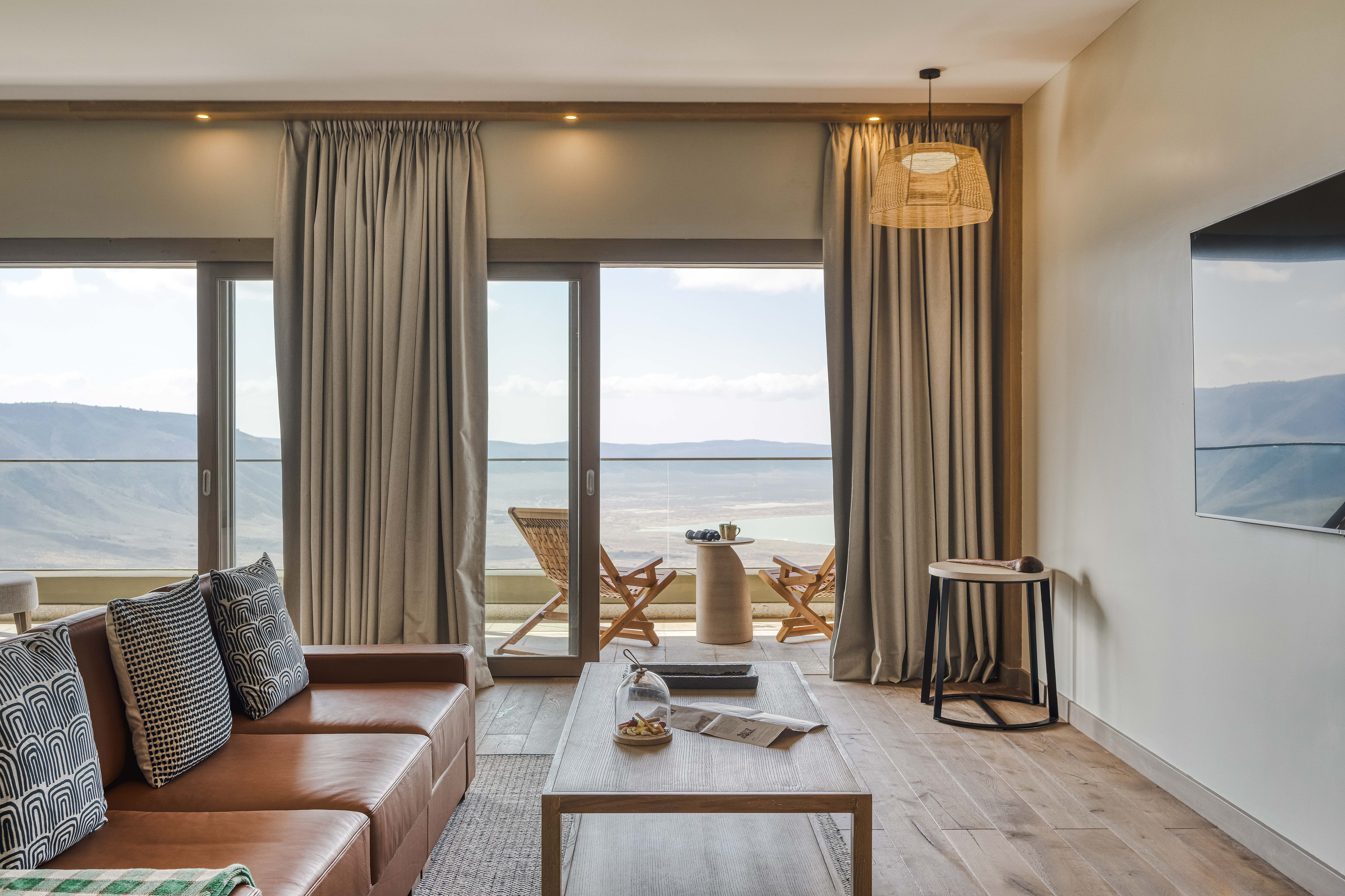 Living room with leather sofa, wood table, balcony, and lake mountain view.