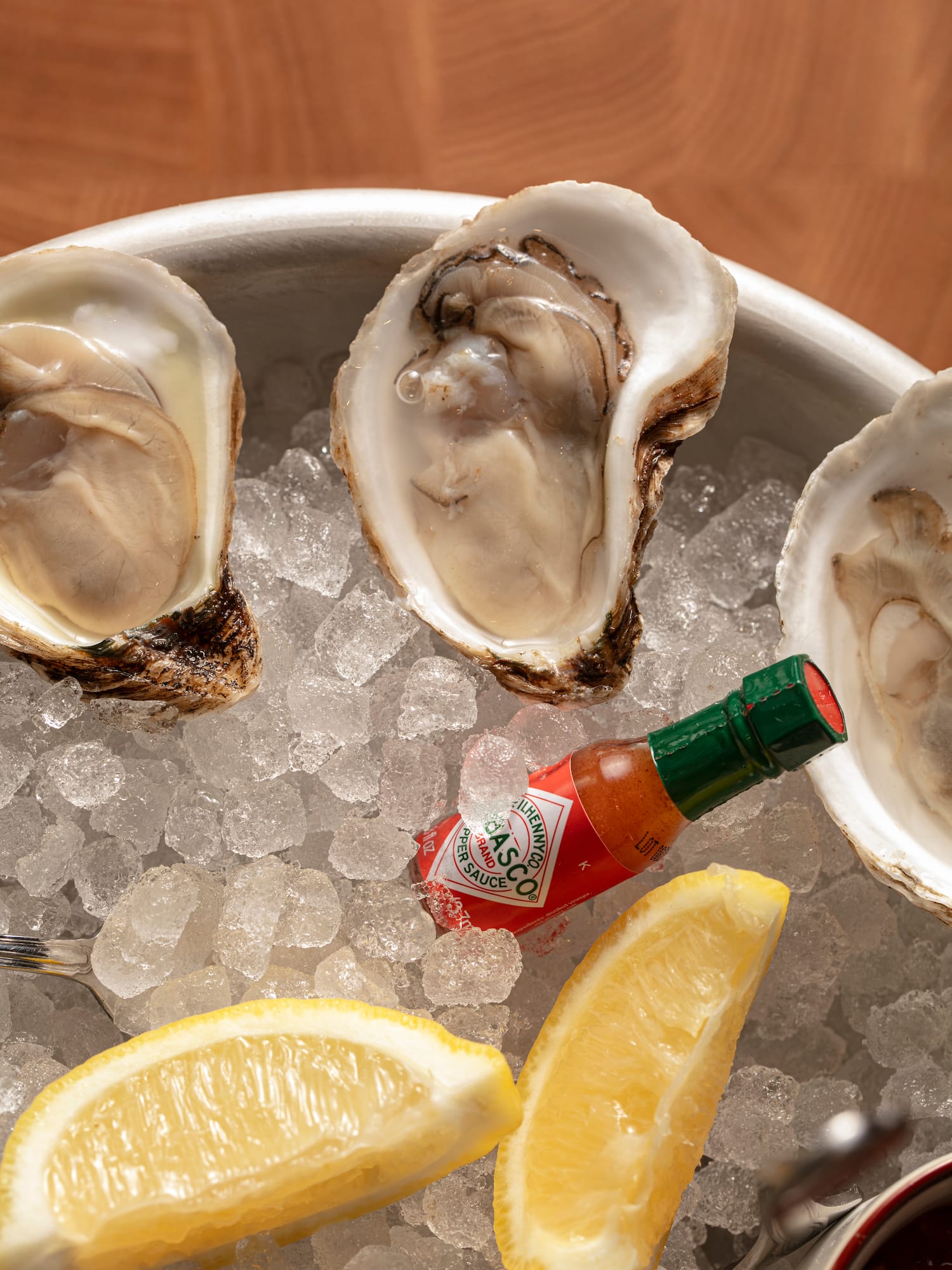 a bowl of oysters on ice with lemons and sauce