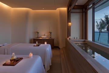 a room with a bathtub and tables with candles