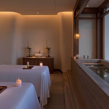 a room with a bathtub and tables with candles