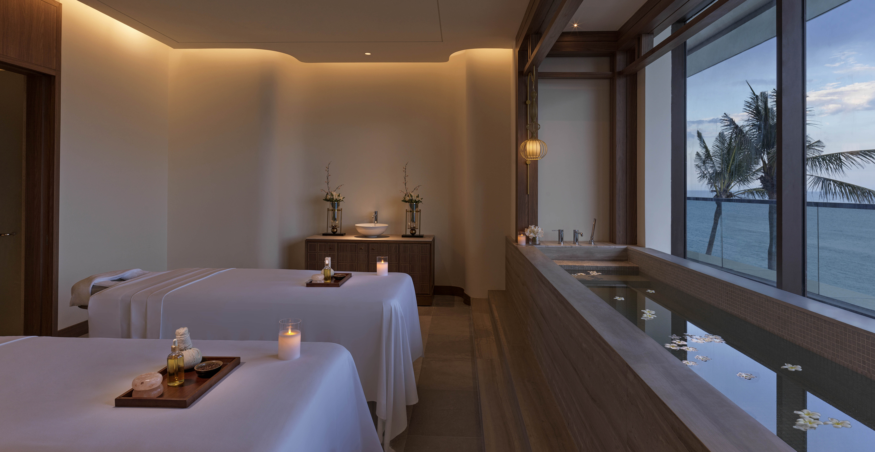 a room with a bathtub and tables with candles