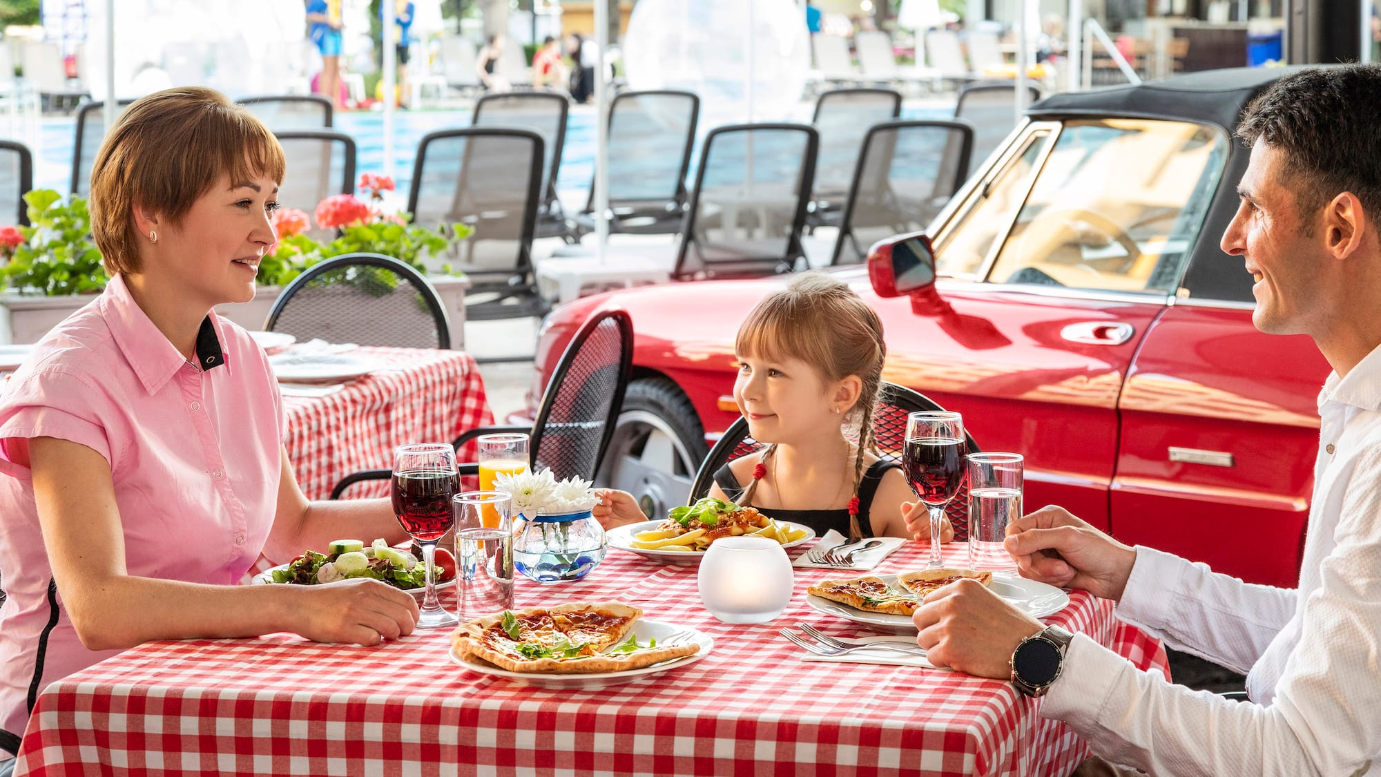 a man and woman sitting at a table with a girl eating pizza