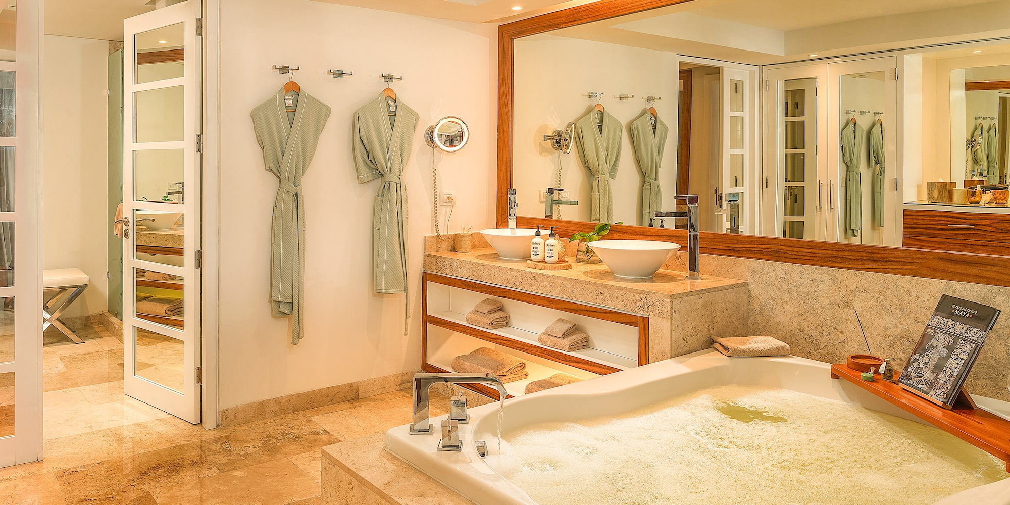 Spa-like bathroom with bubbling tub, dual vessel sinks, marble vanity, and robes.