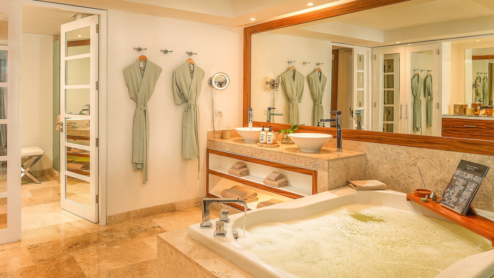 Spa-like bathroom with bubbling tub, dual vessel sinks, marble vanity, and robes.