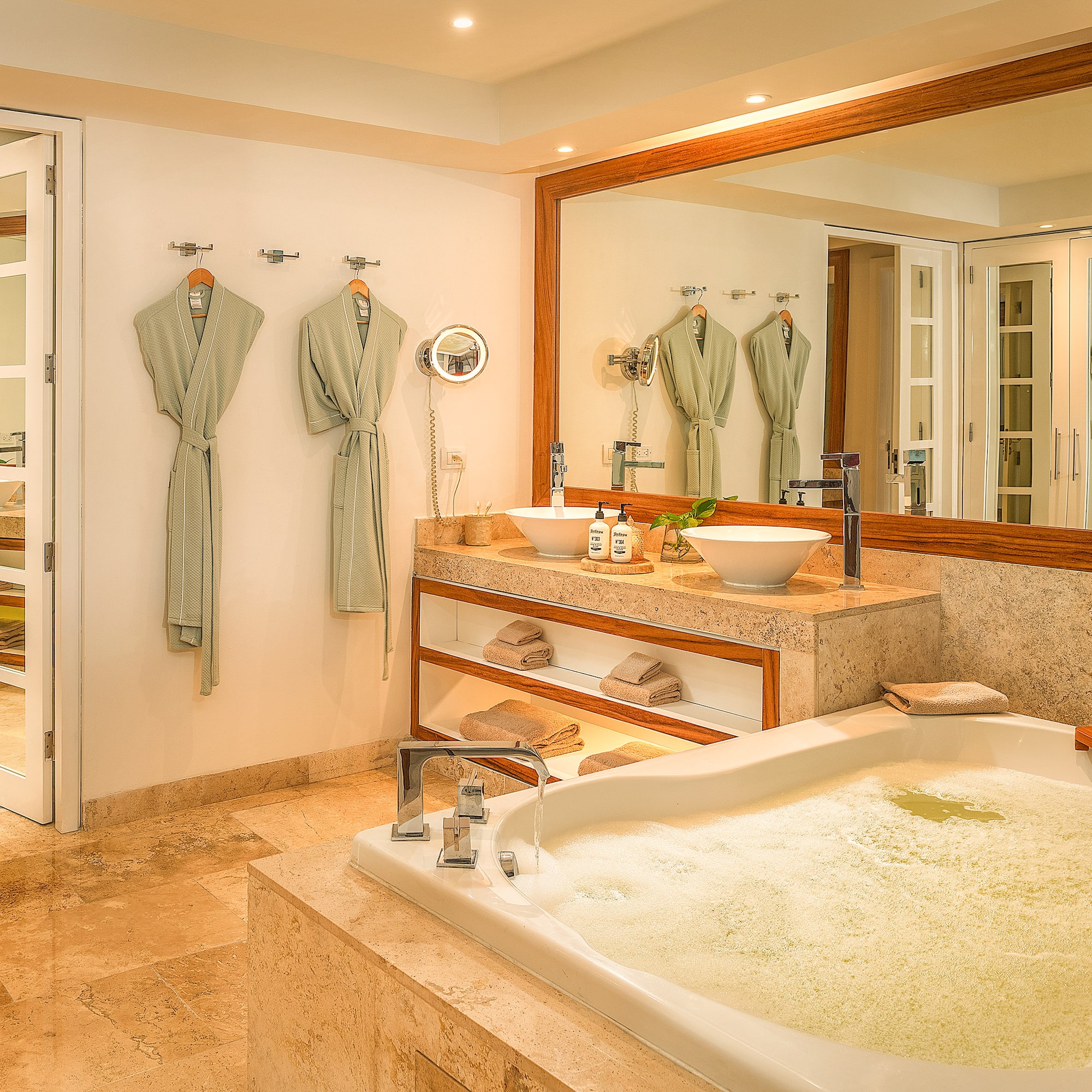 Spa-like bathroom with bubbling tub, dual vessel sinks, marble vanity, and robes.