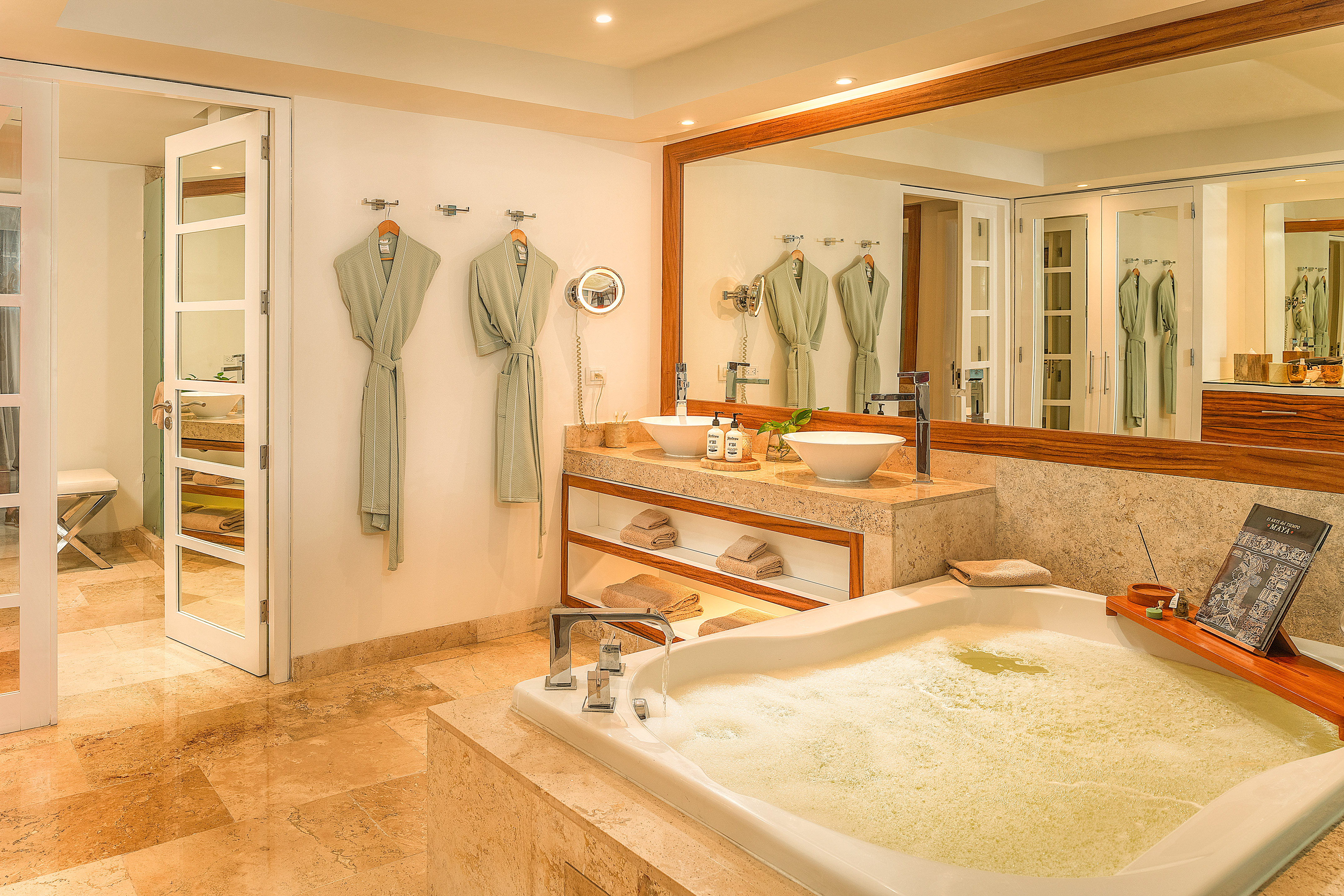 Spa-like bathroom with bubbling tub, dual vessel sinks, marble vanity, and robes.