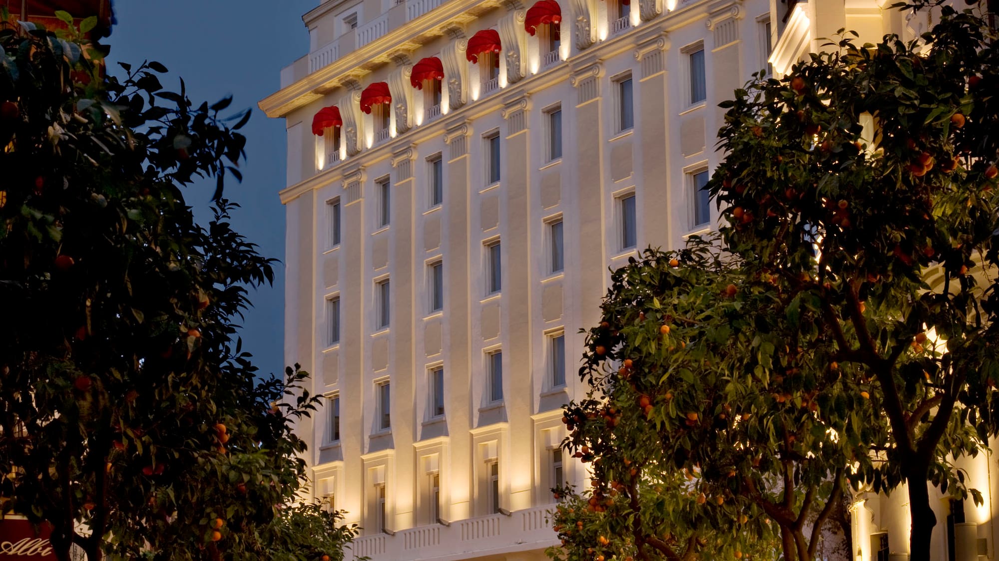 a white building with red awnings and trees
