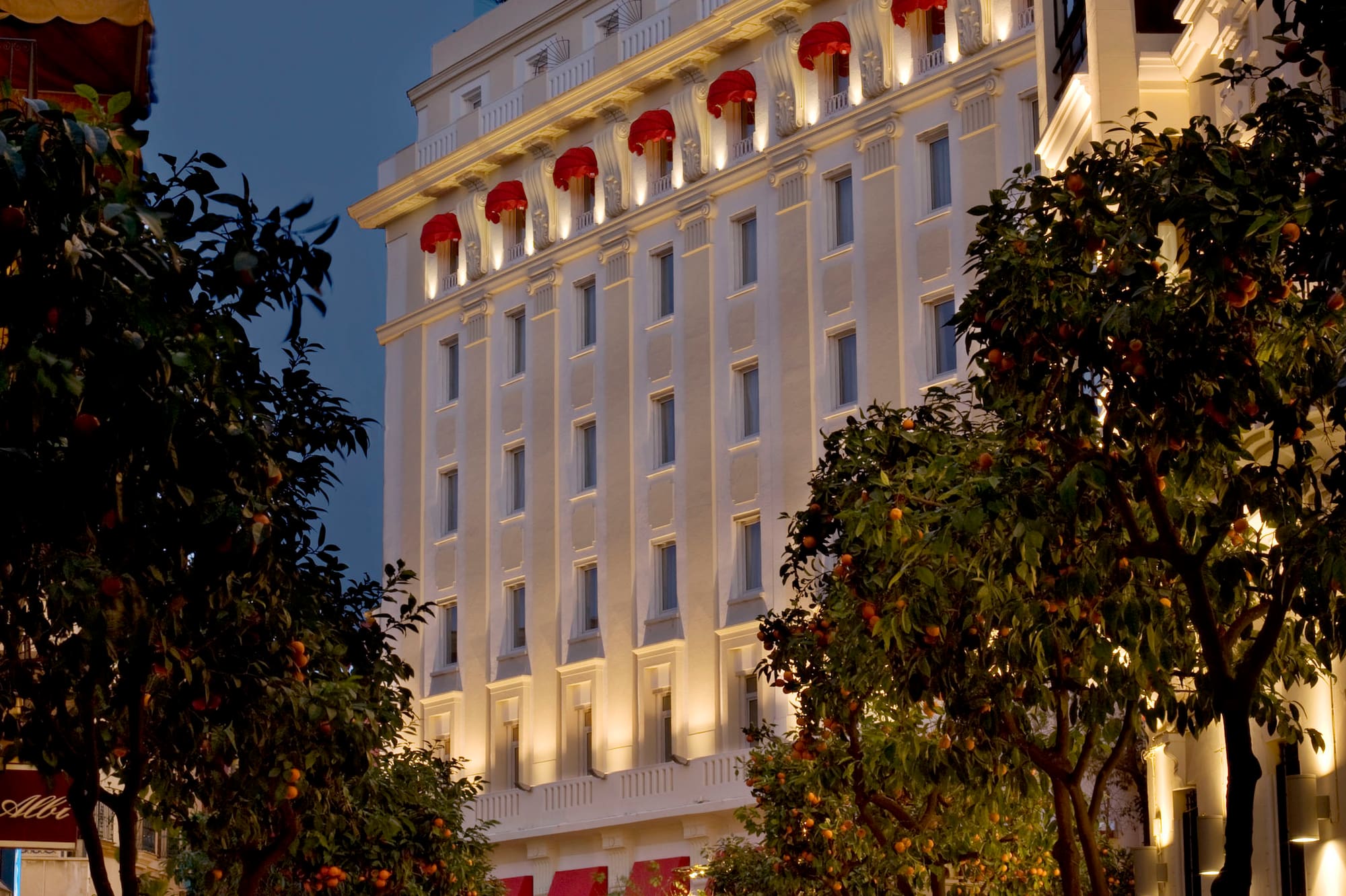 a white building with red awnings and trees