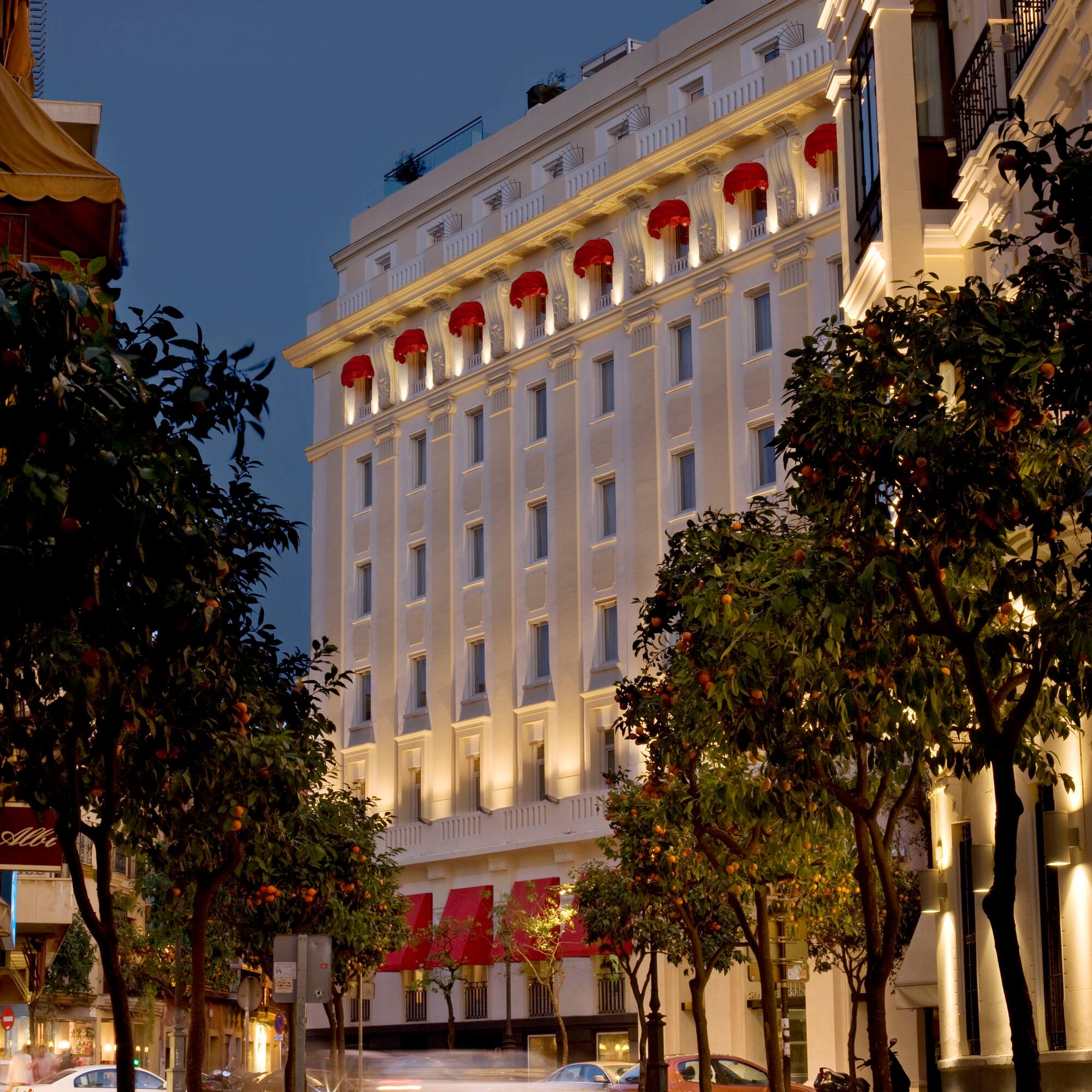 a white building with red awnings and trees