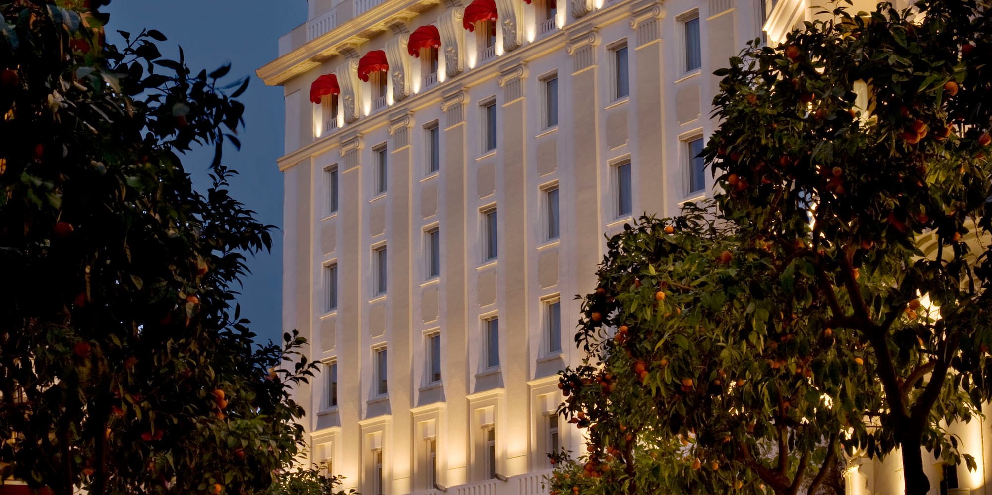 a white building with red awnings and trees