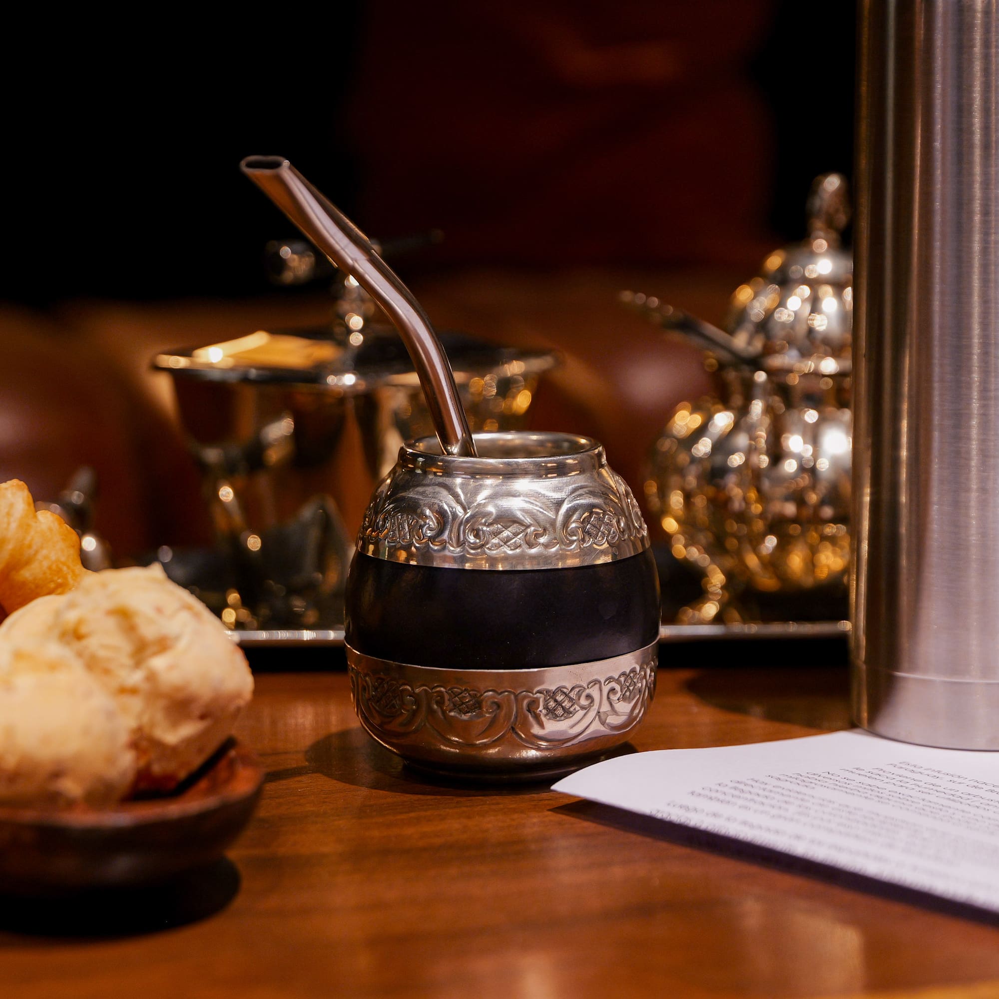 a silver and black gourd with a straw on a table