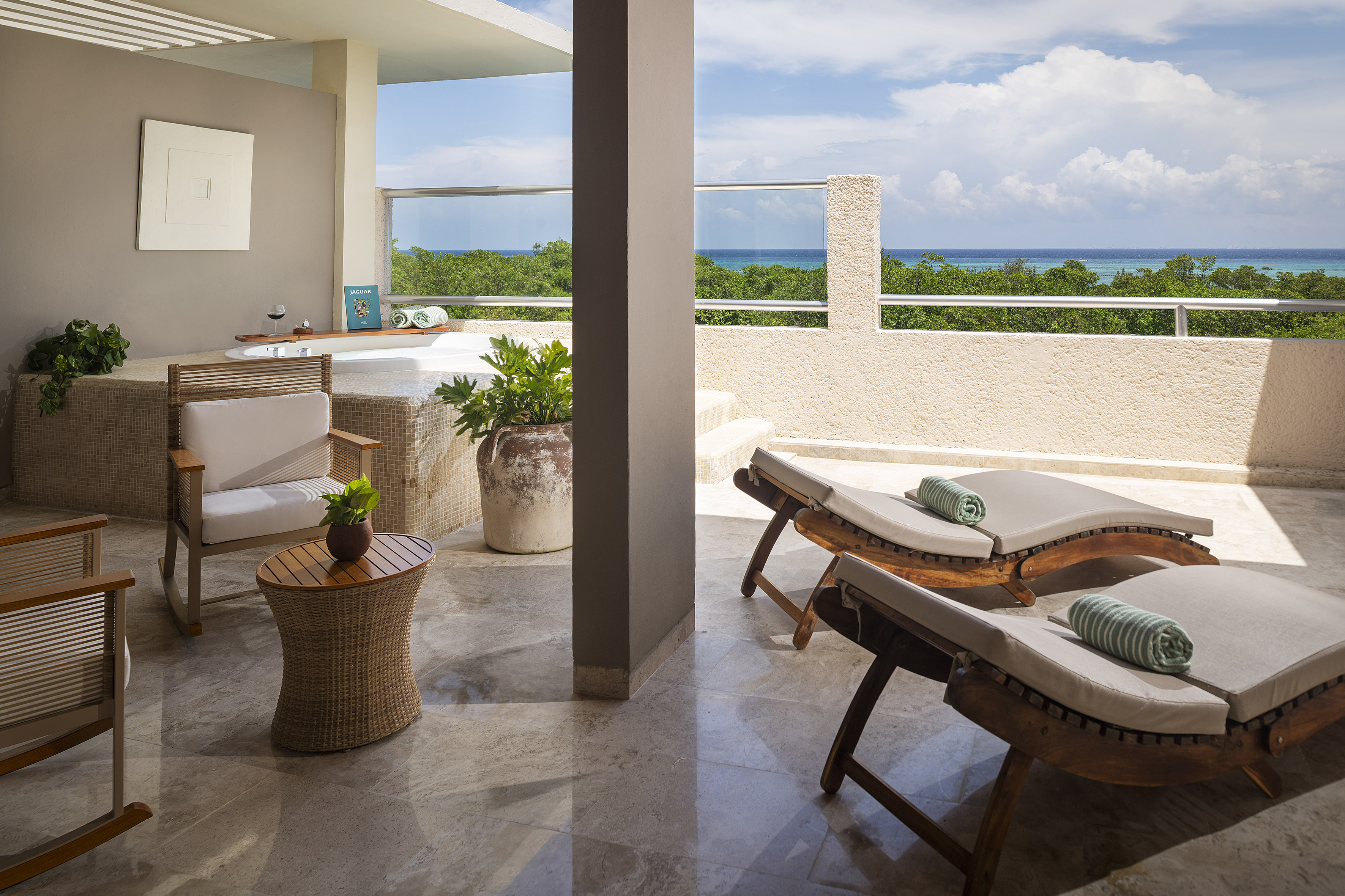 Luxury balcony with ocean view, outdoor jacuzzi, and comfortable lounge chairs.