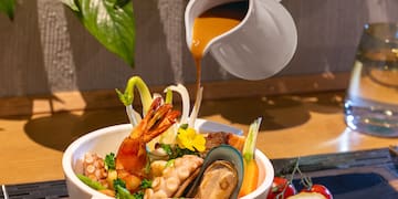 a bowl of seafood with sauce being poured into it
