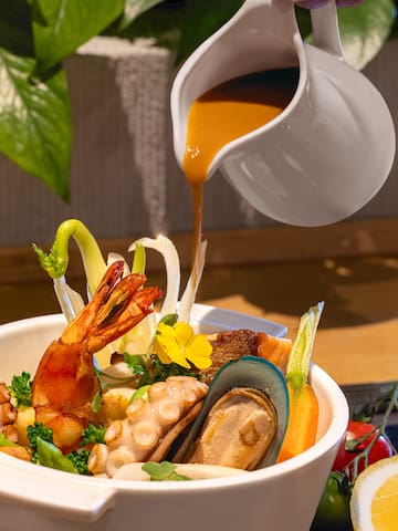 a bowl of seafood with sauce being poured into it