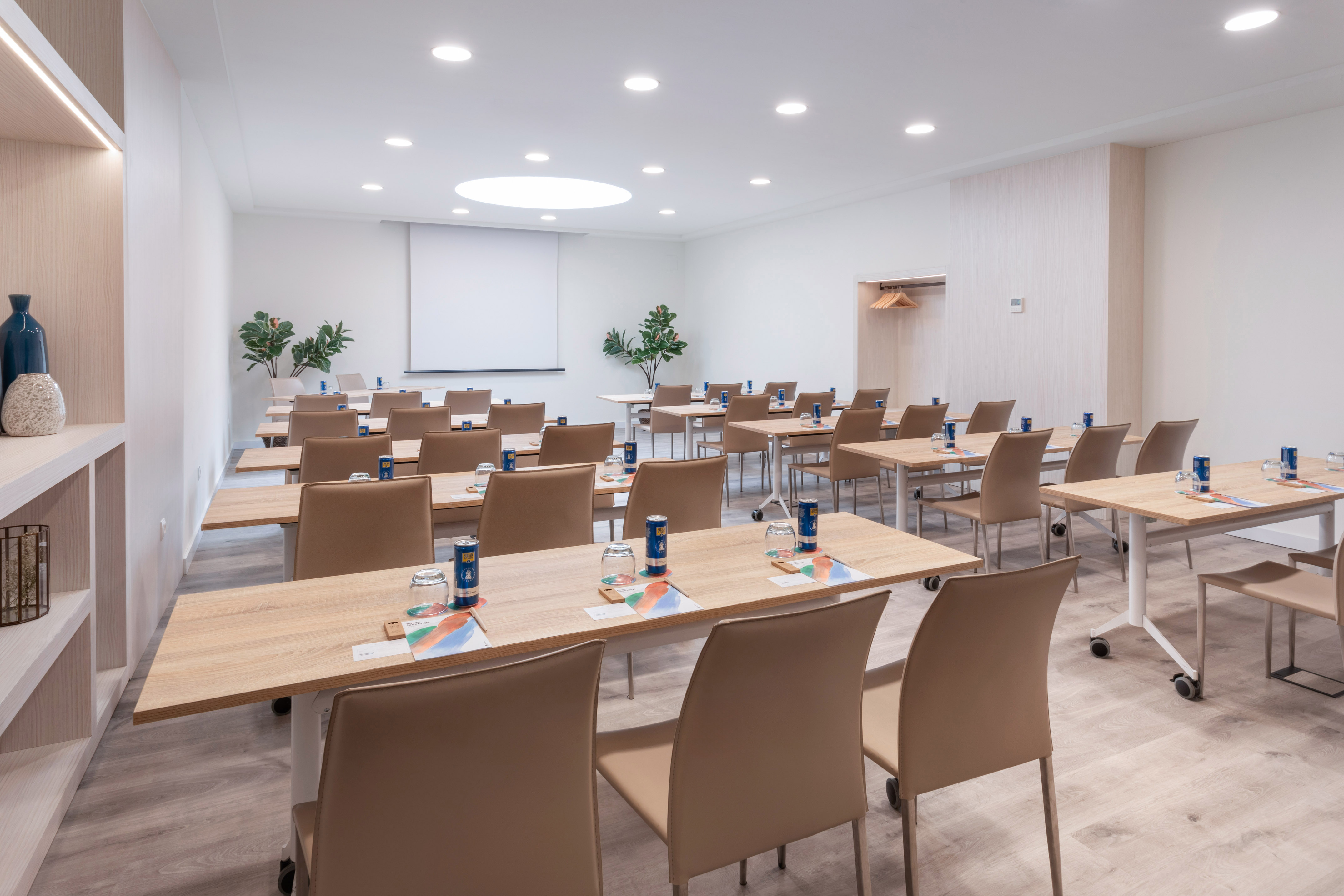 Modern conference room with tables, brown chairs, and a projector screen.