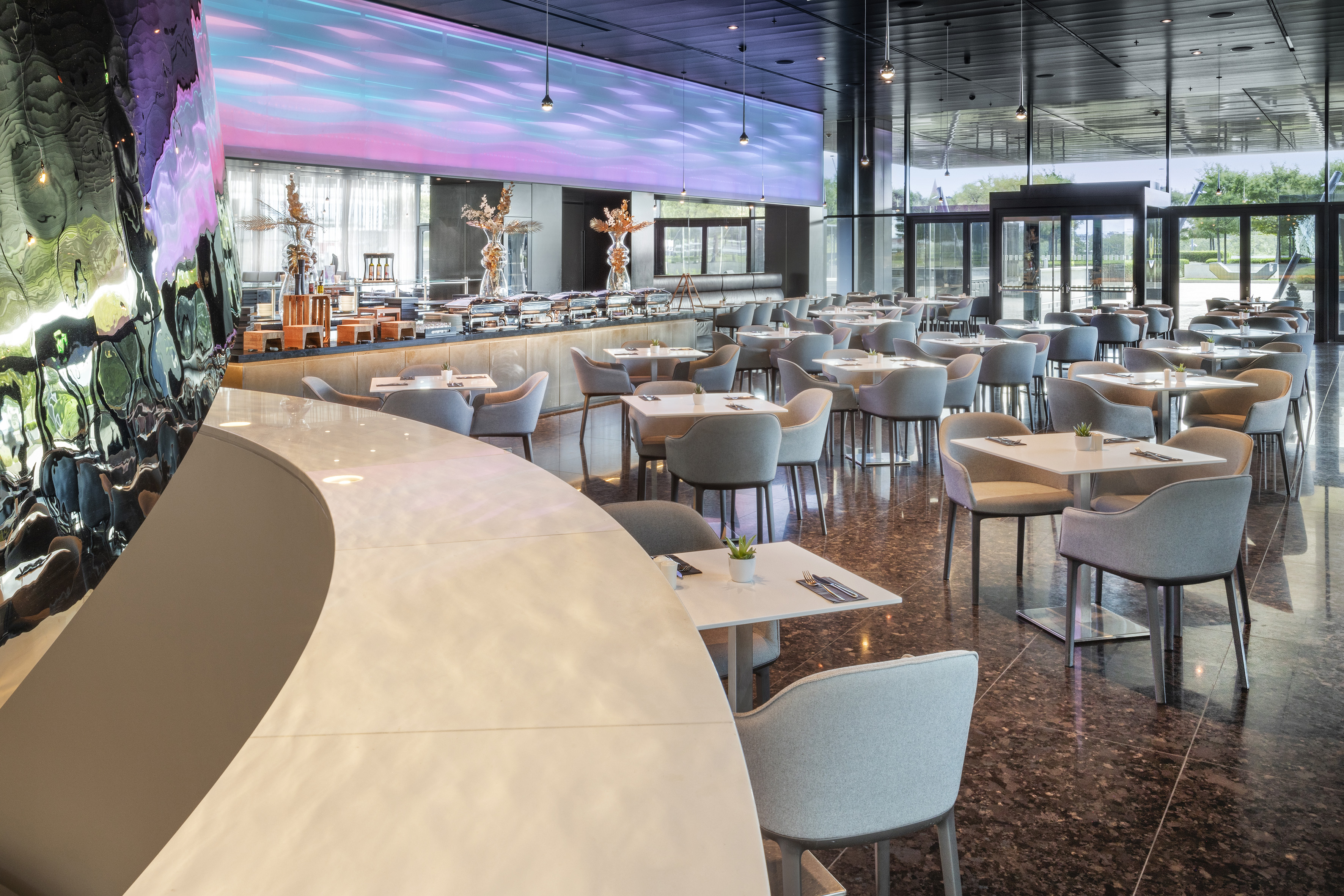 Modern restaurant dining area with buffet and vibrant digital art wall.