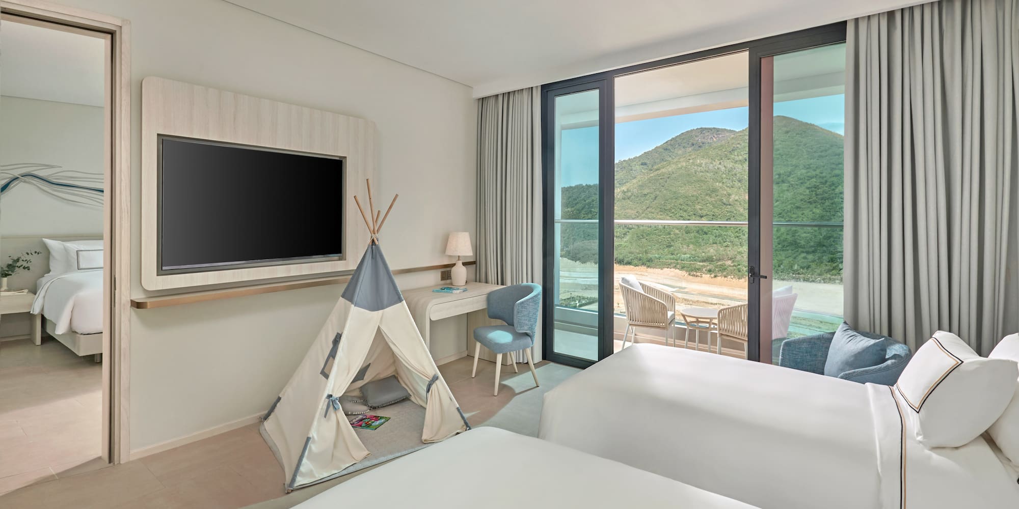 Family hotel room with kids' teepee, two beds, balcony, and mountain view.