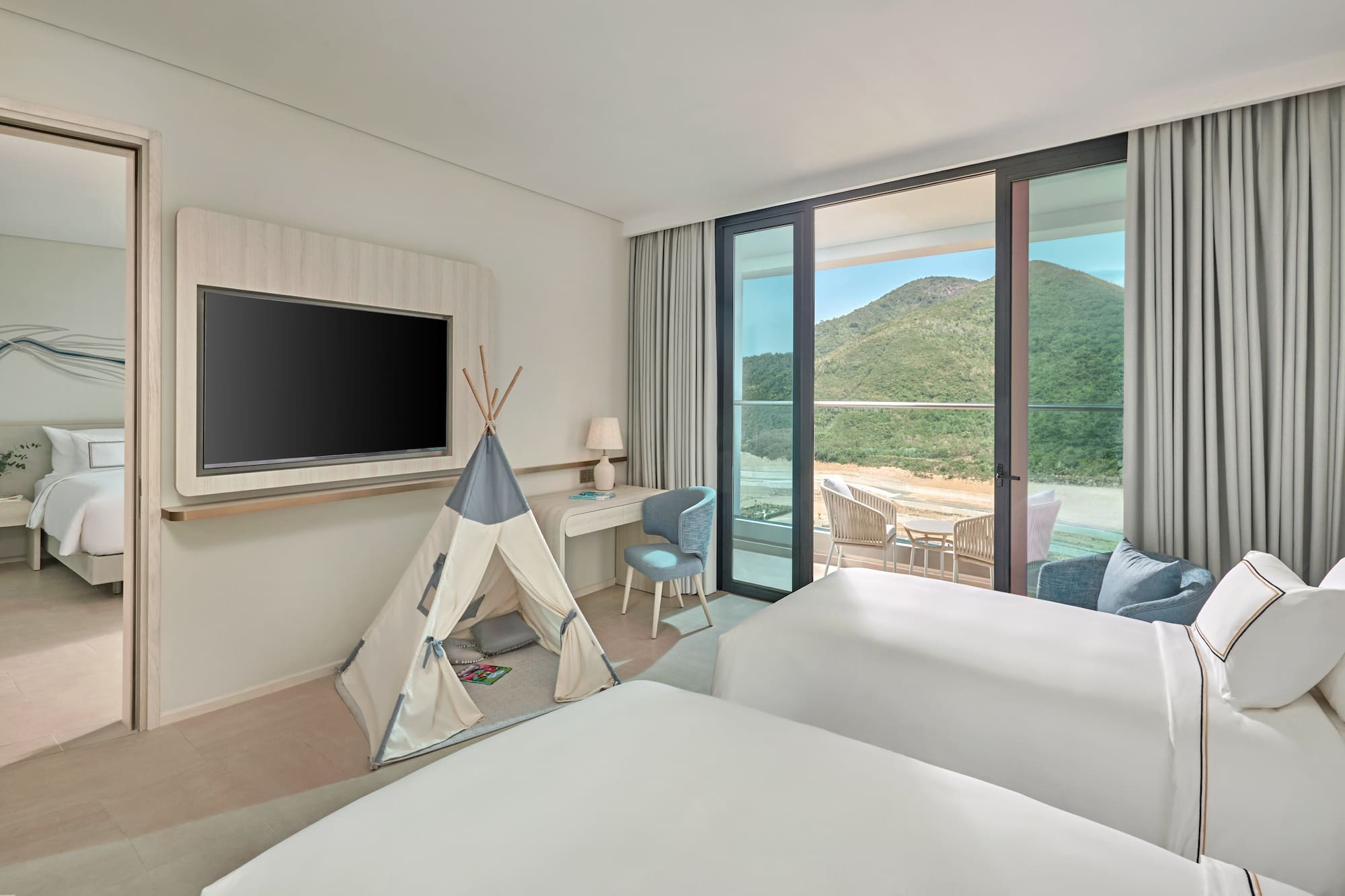Family hotel room with kids' teepee, two beds, balcony, and mountain view.