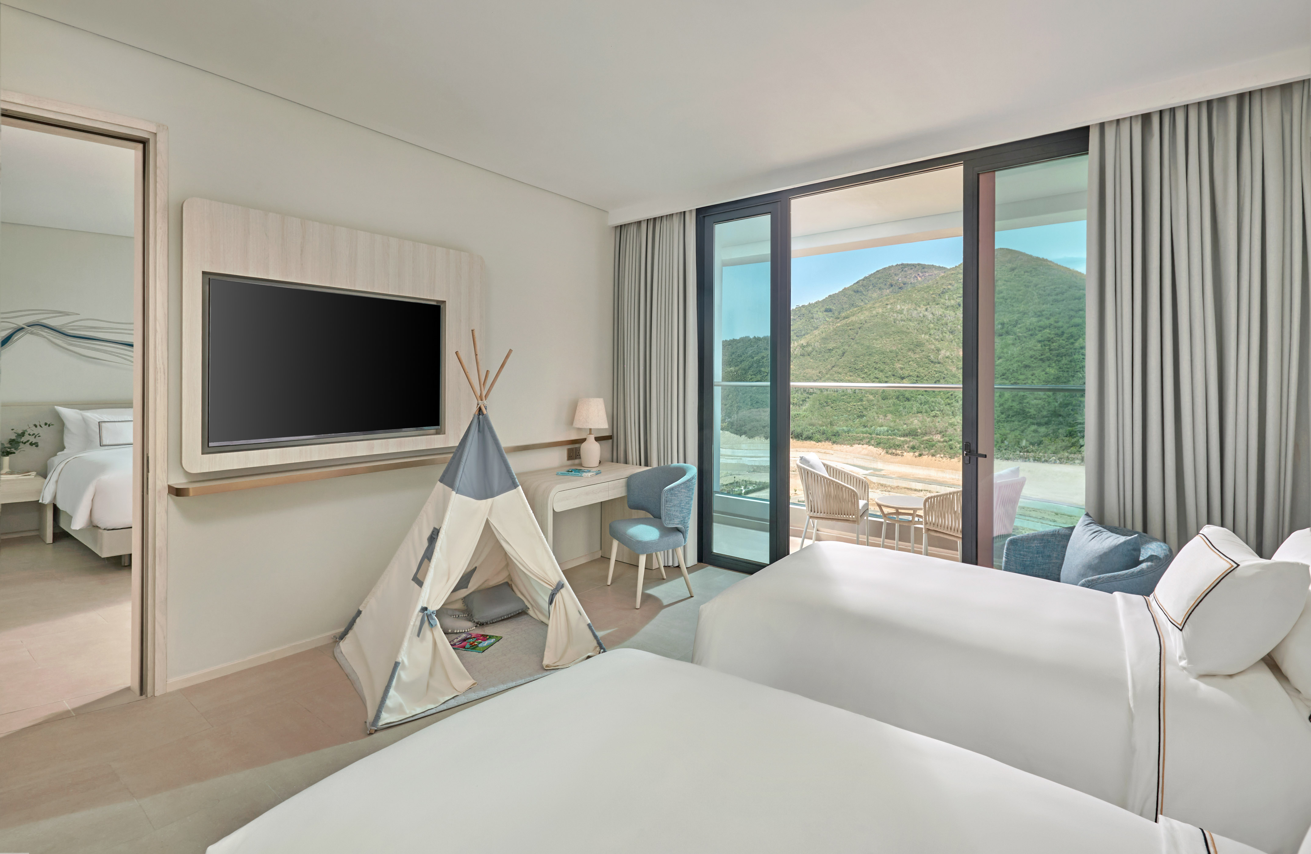 Family hotel room with kids' teepee, two beds, balcony, and mountain view.