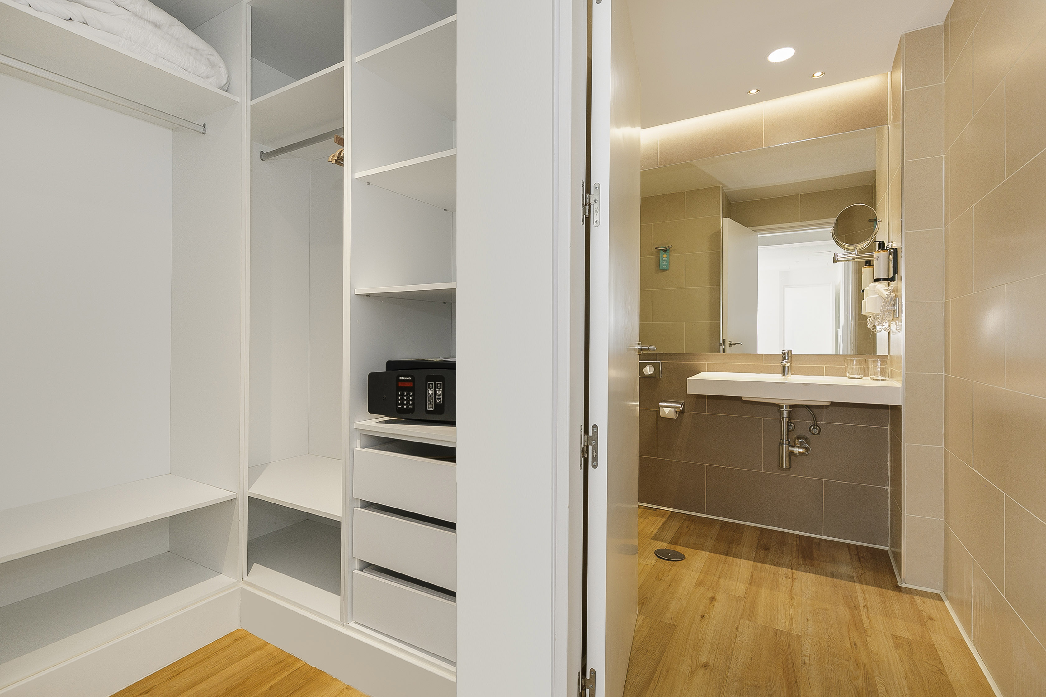 Hotel closet with safe, storage, and modern bathroom vanity.