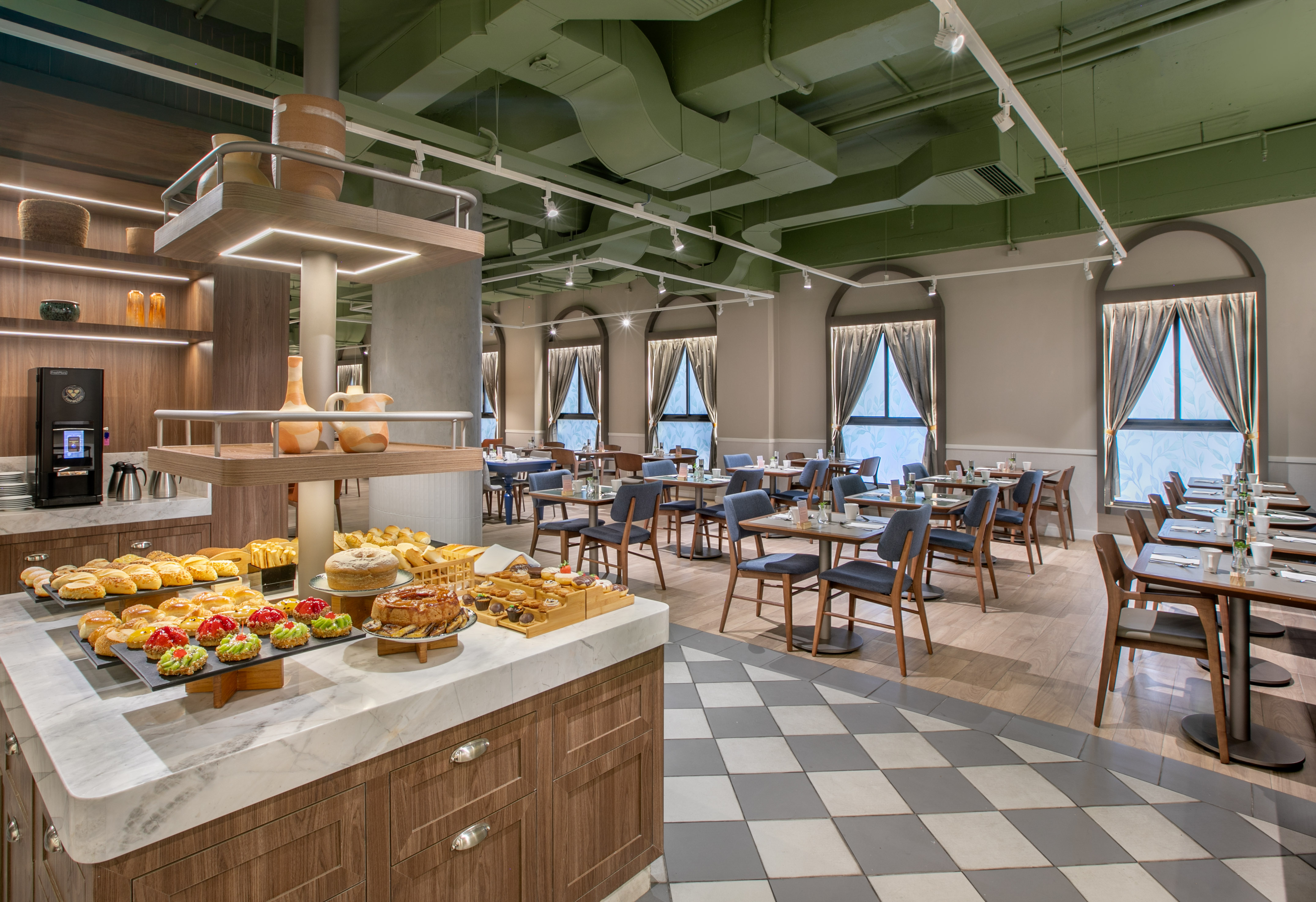 Modern hotel dining room with a breakfast buffet and green ceiling.