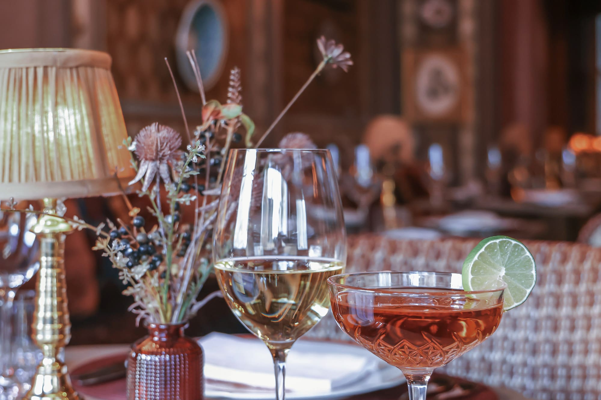 A table set with wine glasses and a vase of flowers.