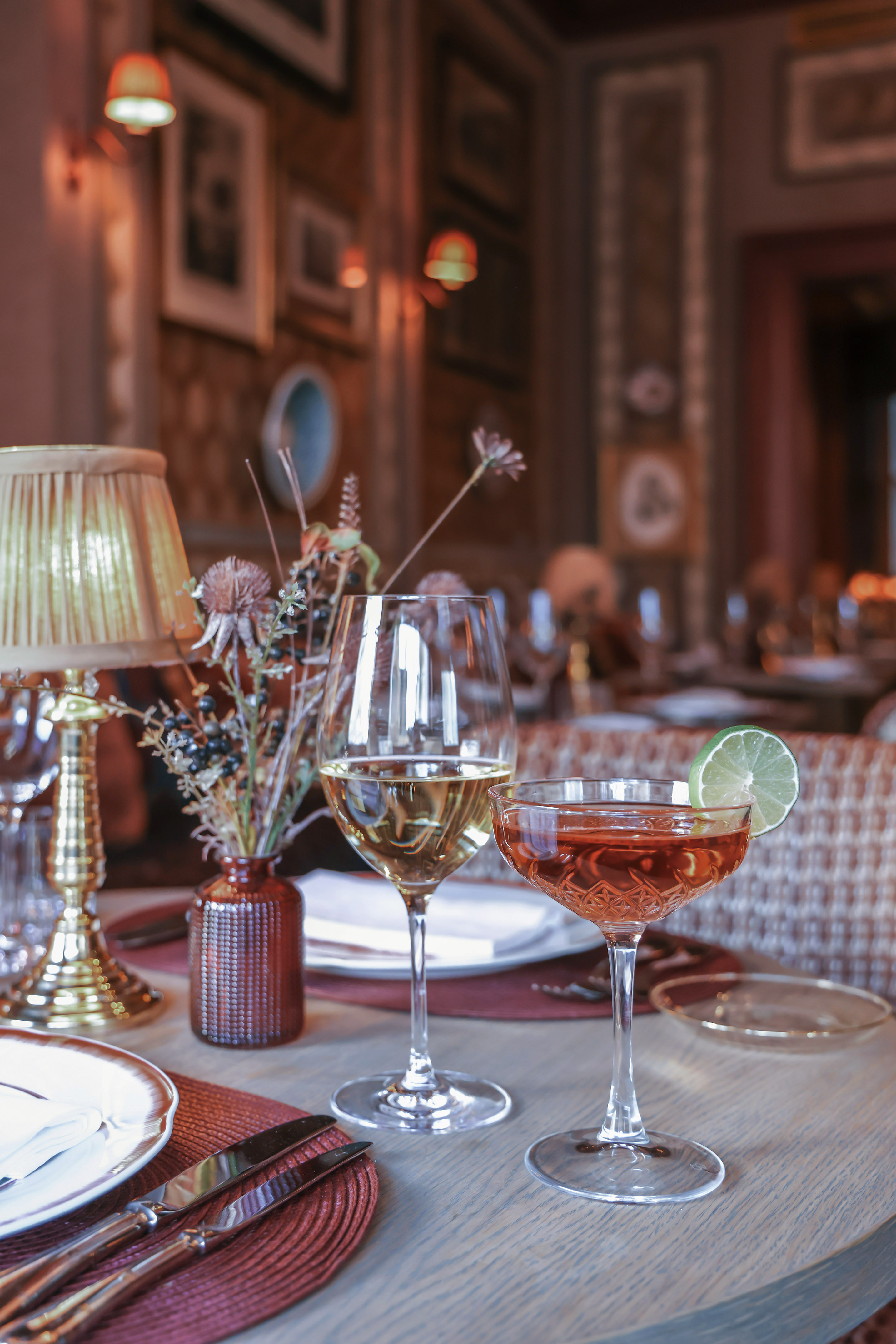 A table set with wine glasses and a vase of flowers.