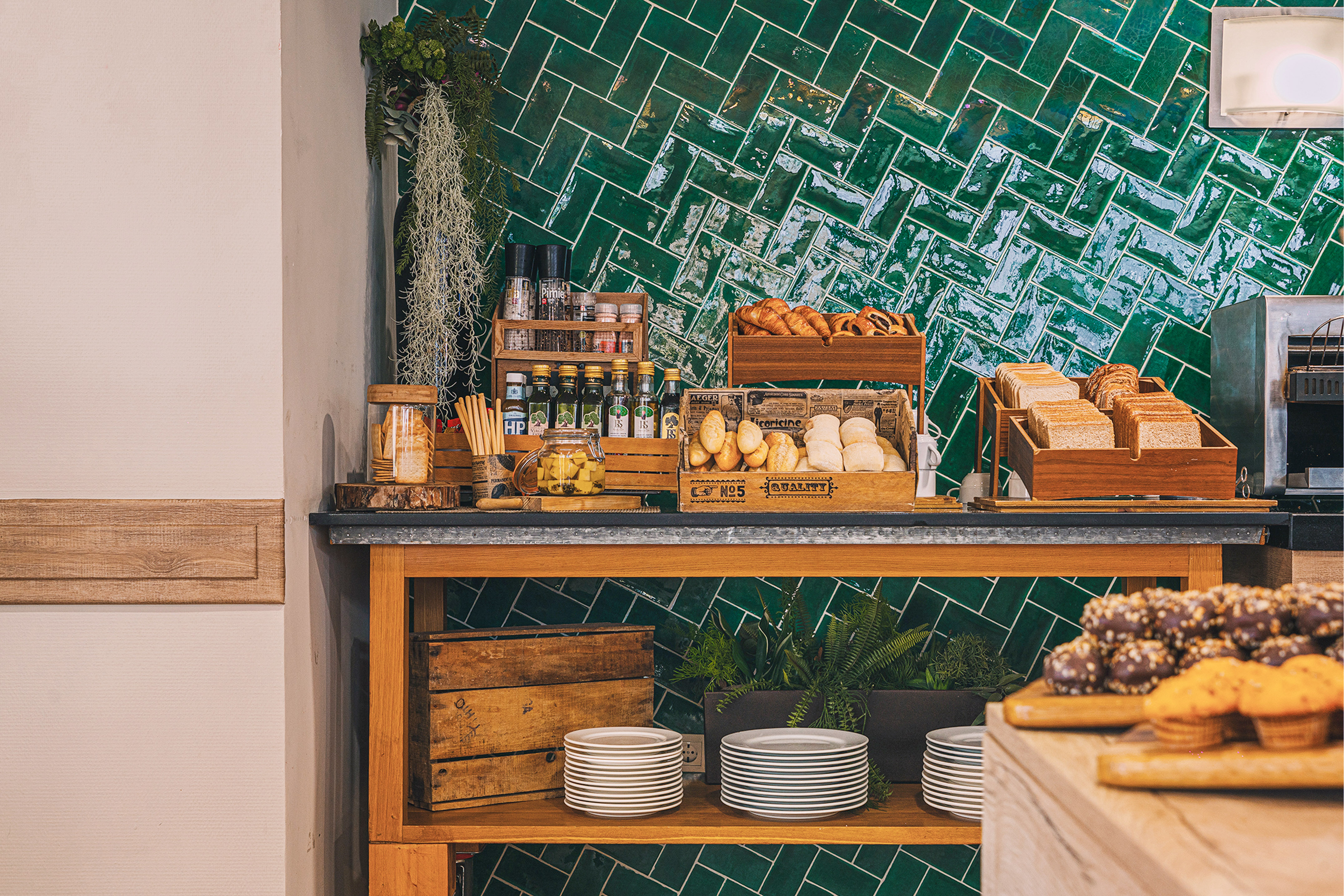 Fresh breakfast buffet with bread, pastries, and green herringbone tiles.
