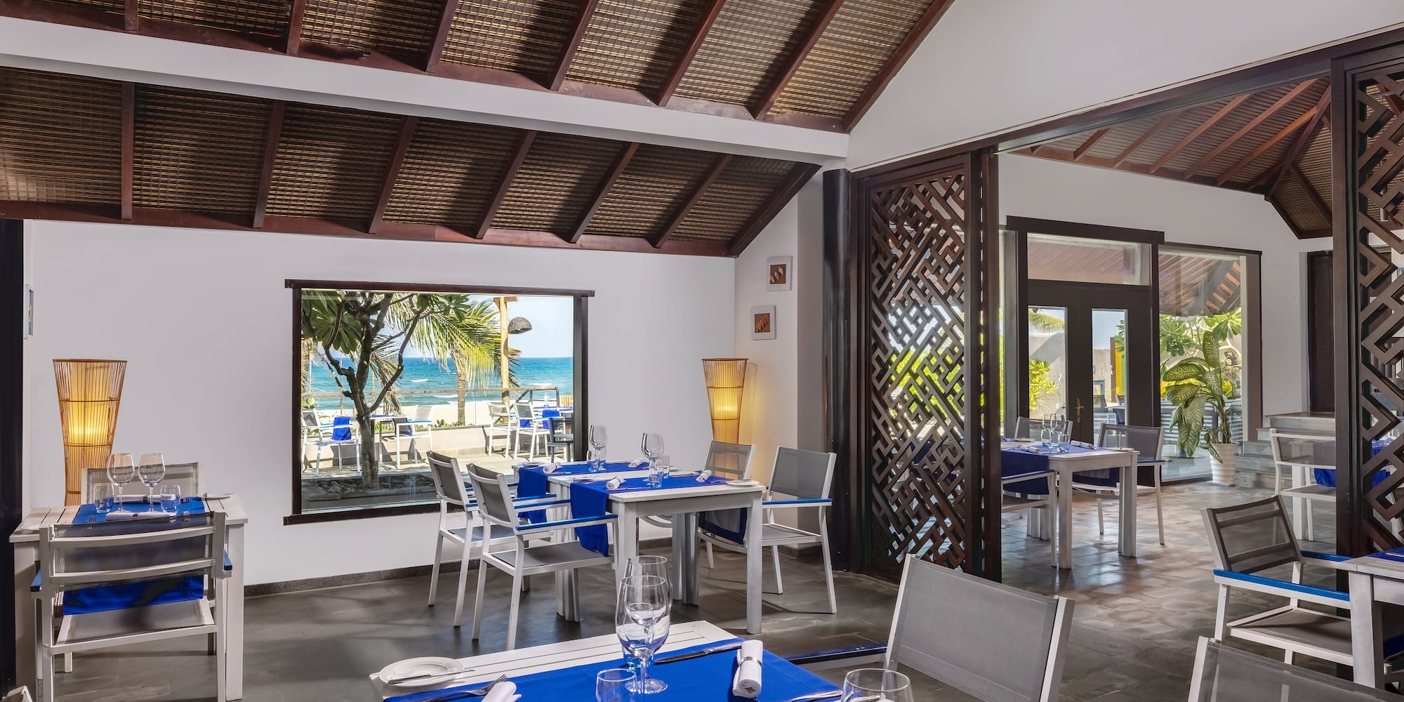 a room with tables and chairs and a view of the ocean