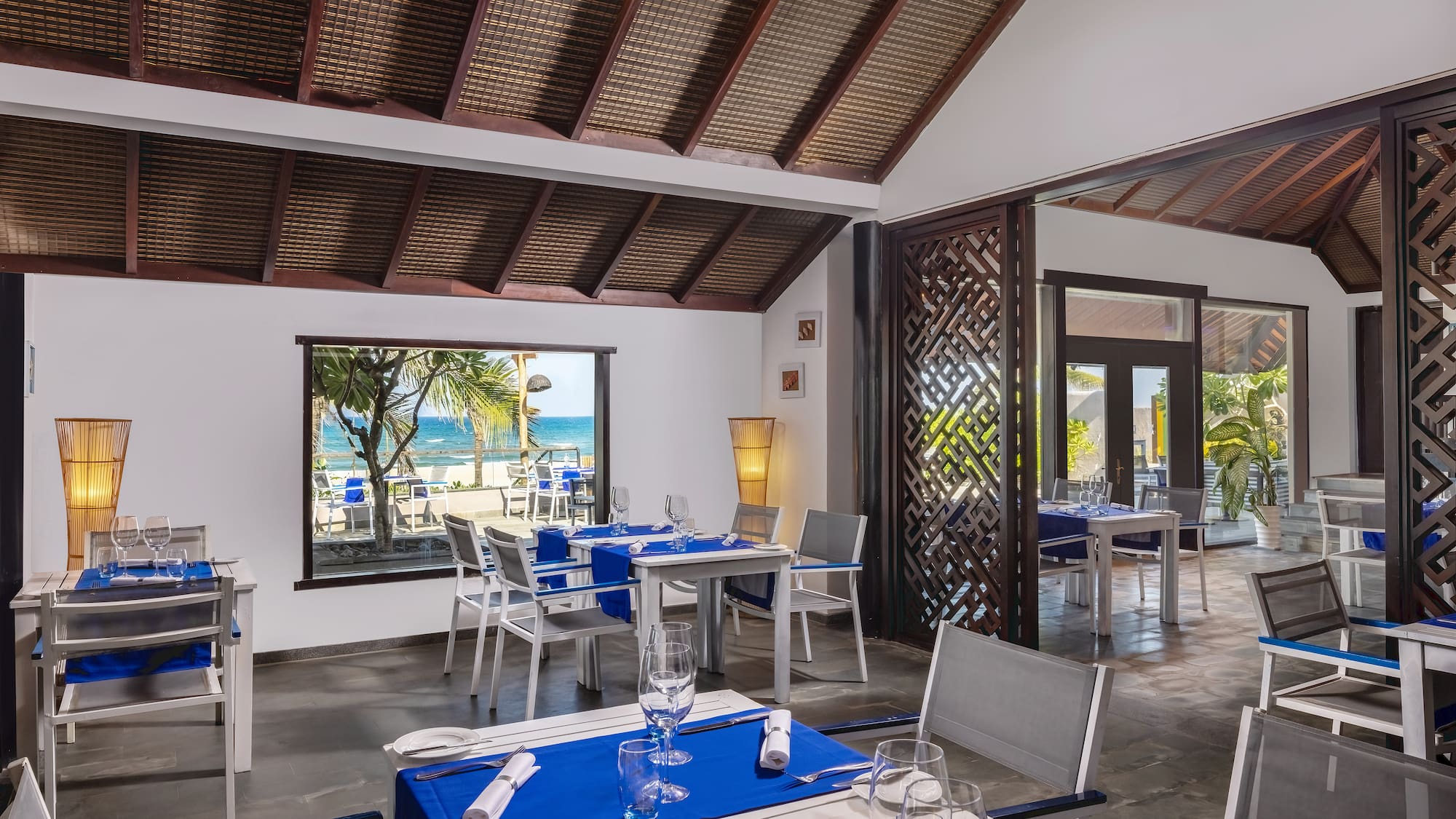 a room with tables and chairs and a view of the ocean
