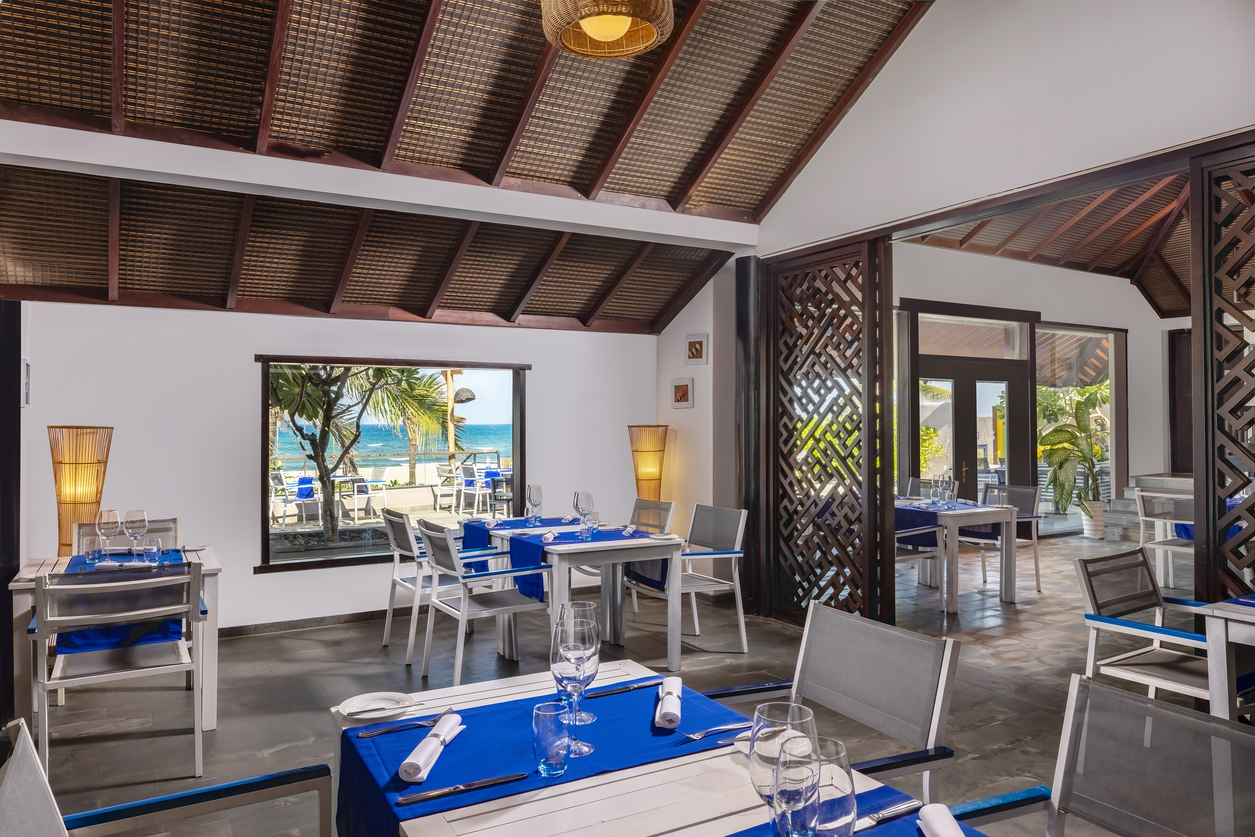 a room with tables and chairs and a view of the ocean