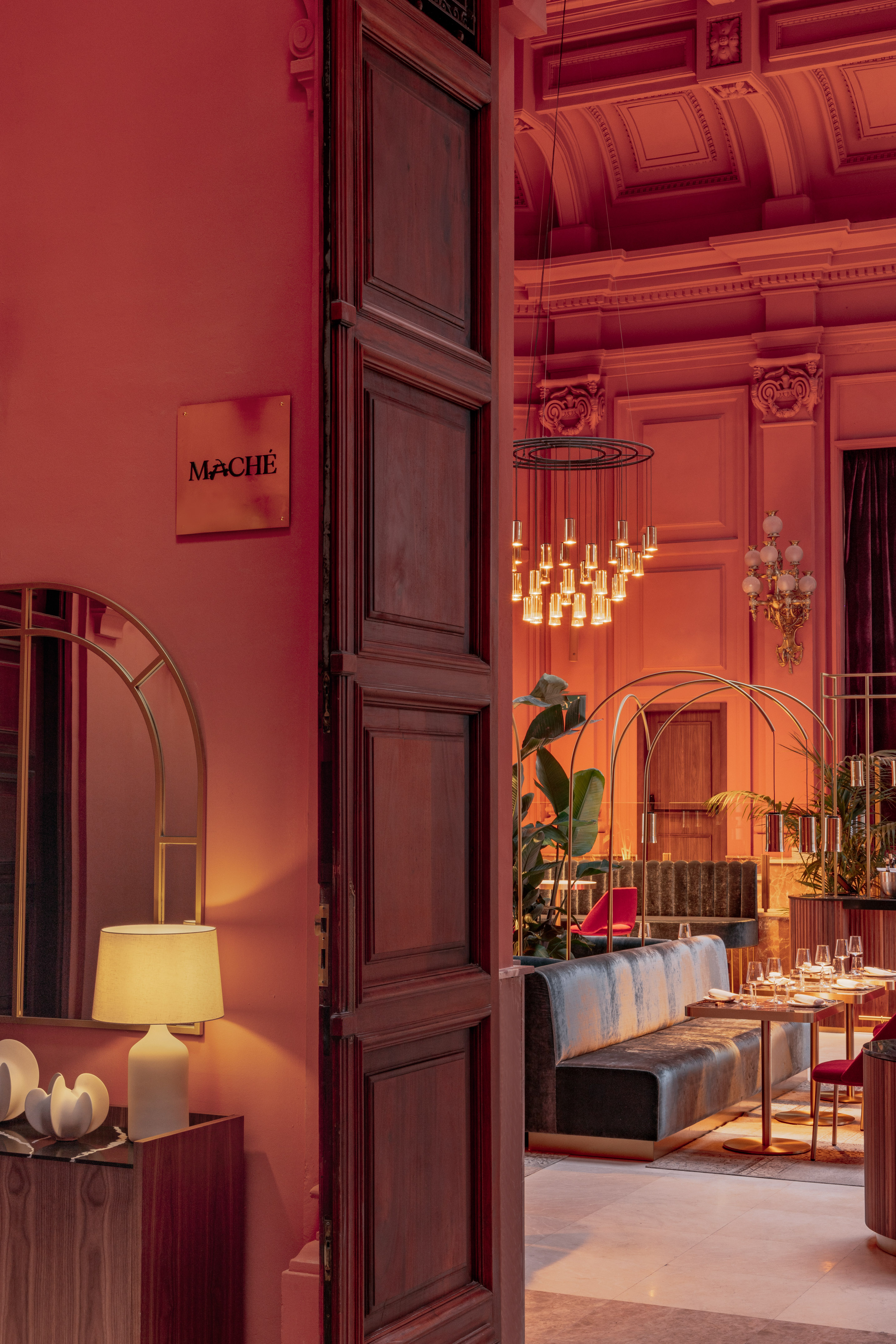 Mache restaurant interior with red walls, modern chandelier, and elegant dining area.