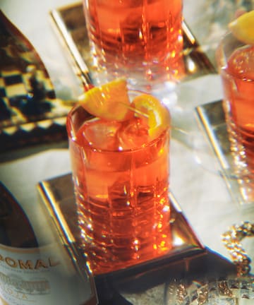 a group of glasses with orange liquid and a slice of lemon