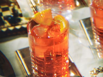 a group of glasses with orange liquid and a slice of lemon