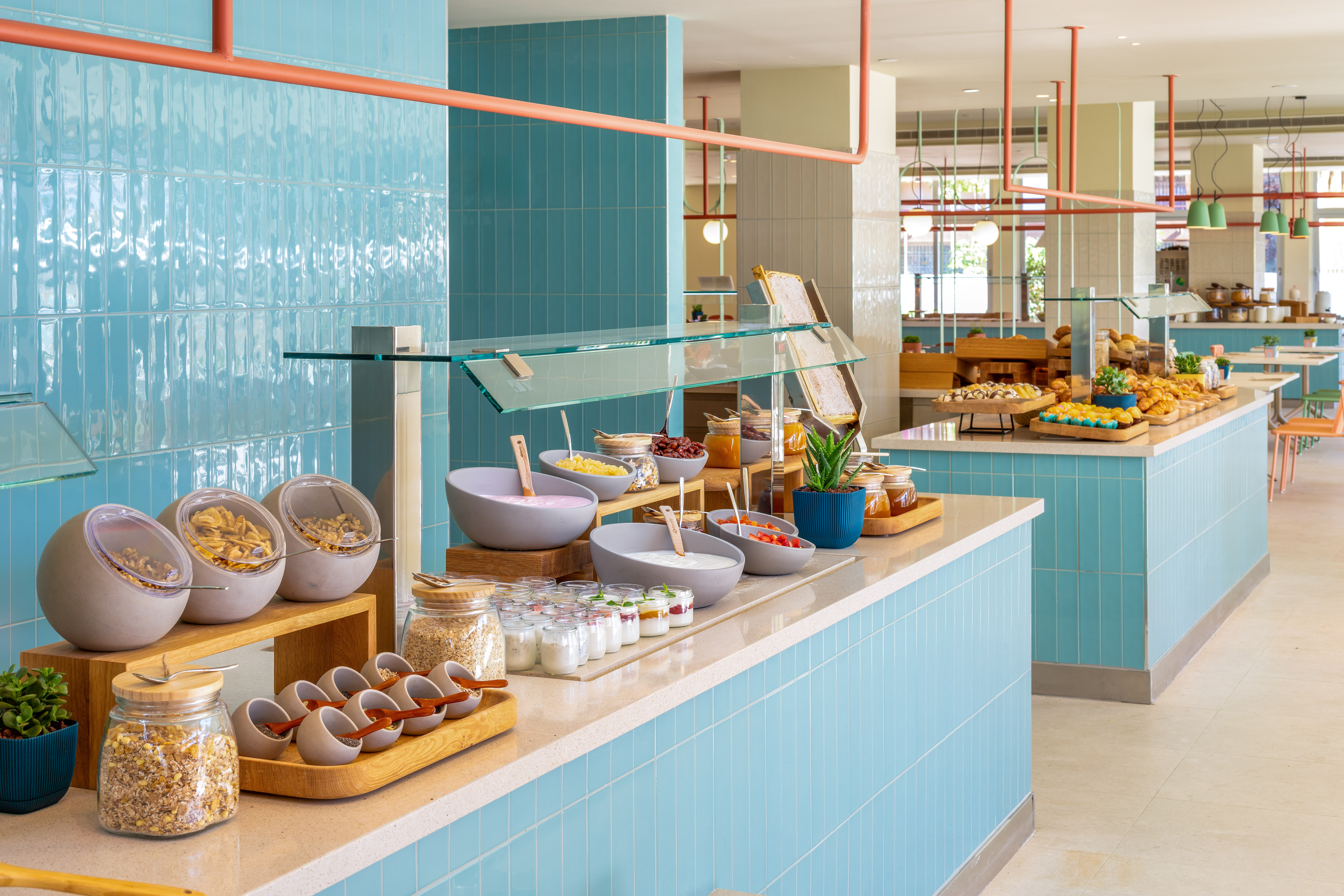 Modern hotel breakfast buffet: cereals, yogurt, fruits, pastries.