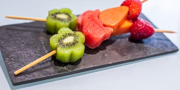 a skewer of fruit on a black plate