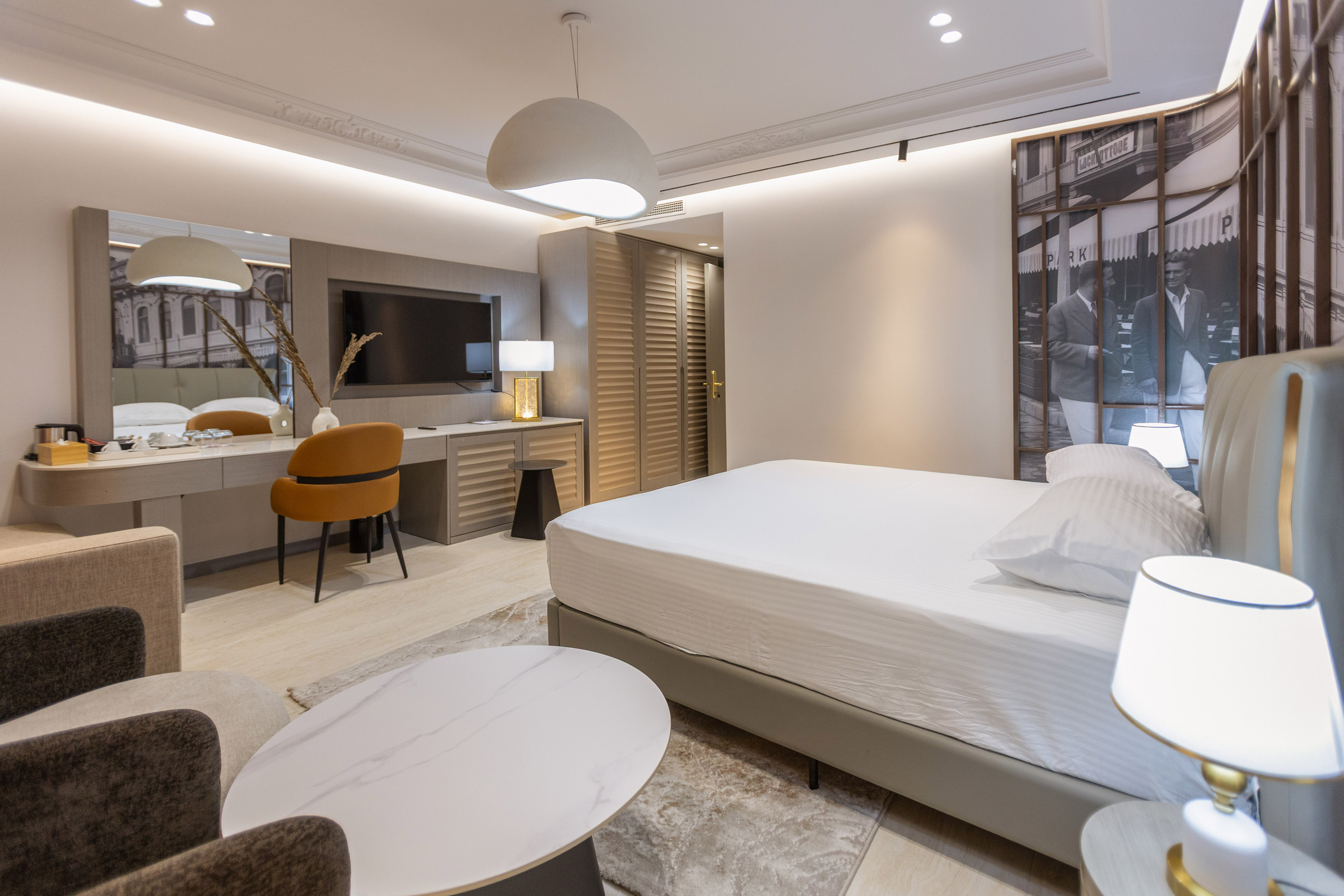 Luxury hotel room with white bed, modern decor, vanity, and city mural. - Shkodër Grand Hotel Europa Affiliated by Meliá, Shkodër