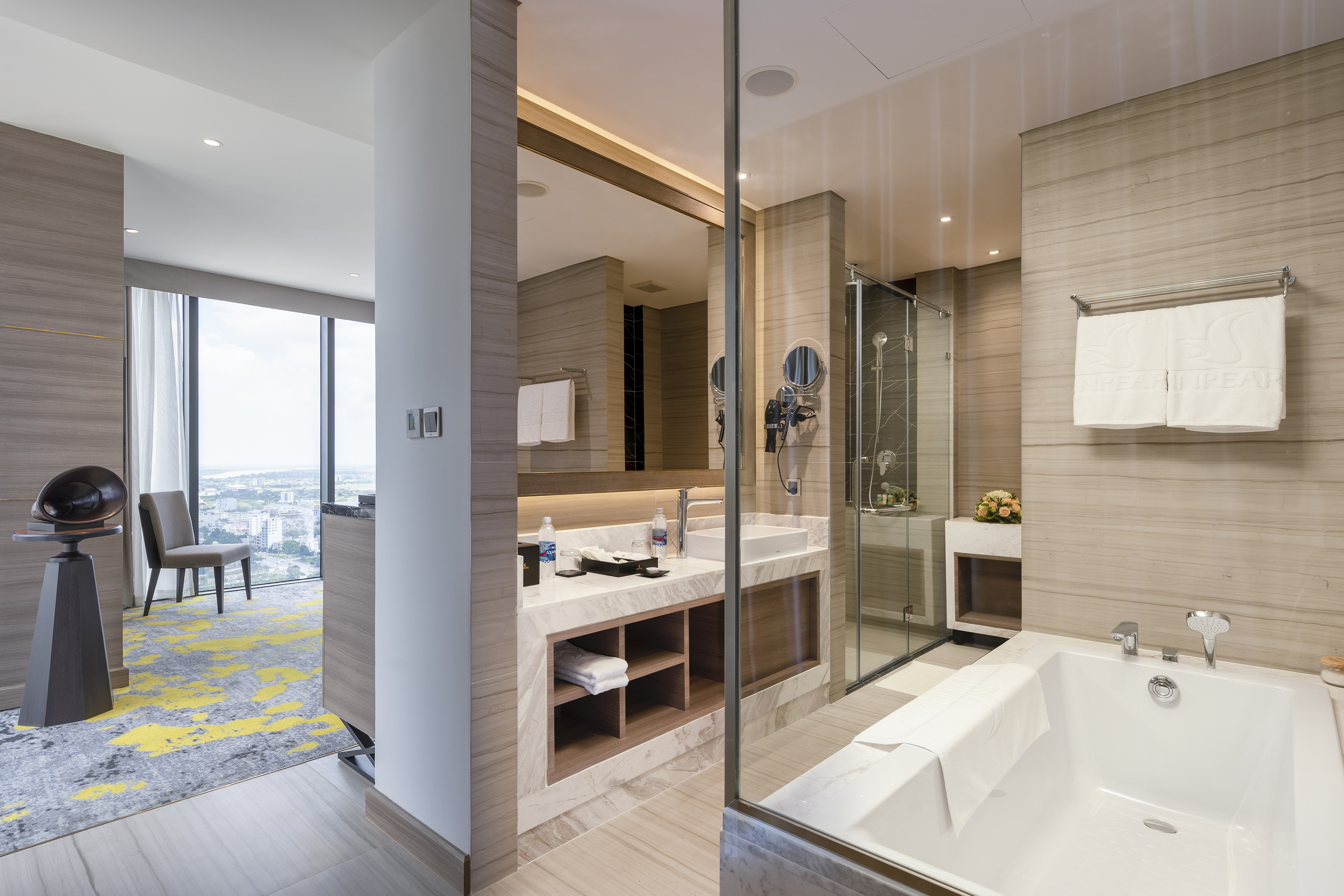 Luxury hotel bathroom with marble tub, glass shower, double vanity, and city view.