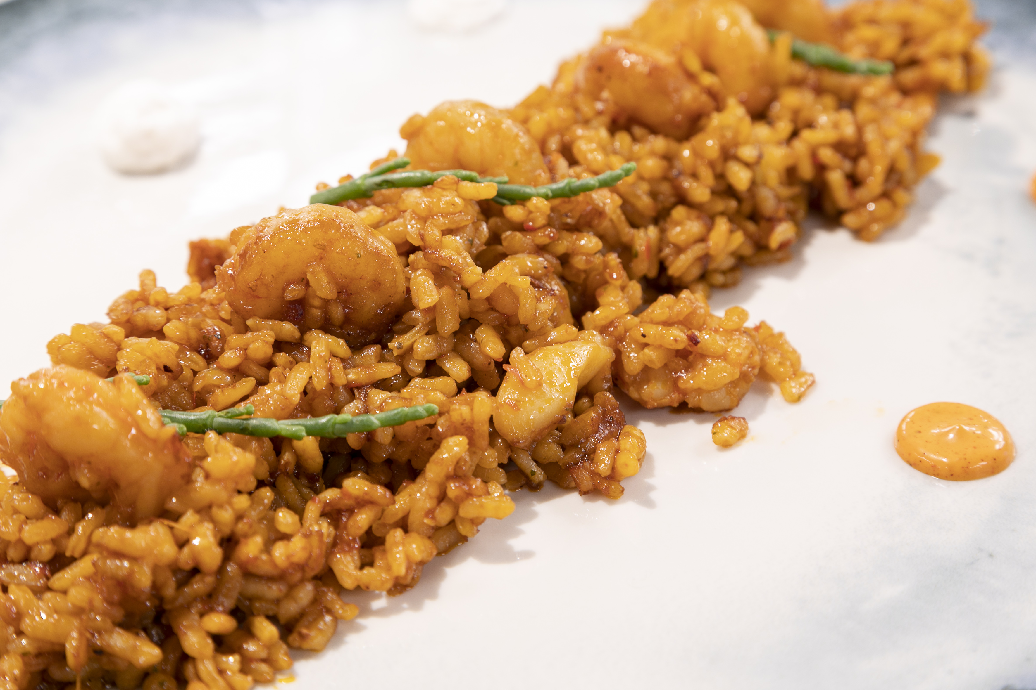 Vibrant orange seafood paella with shrimp and green accents.