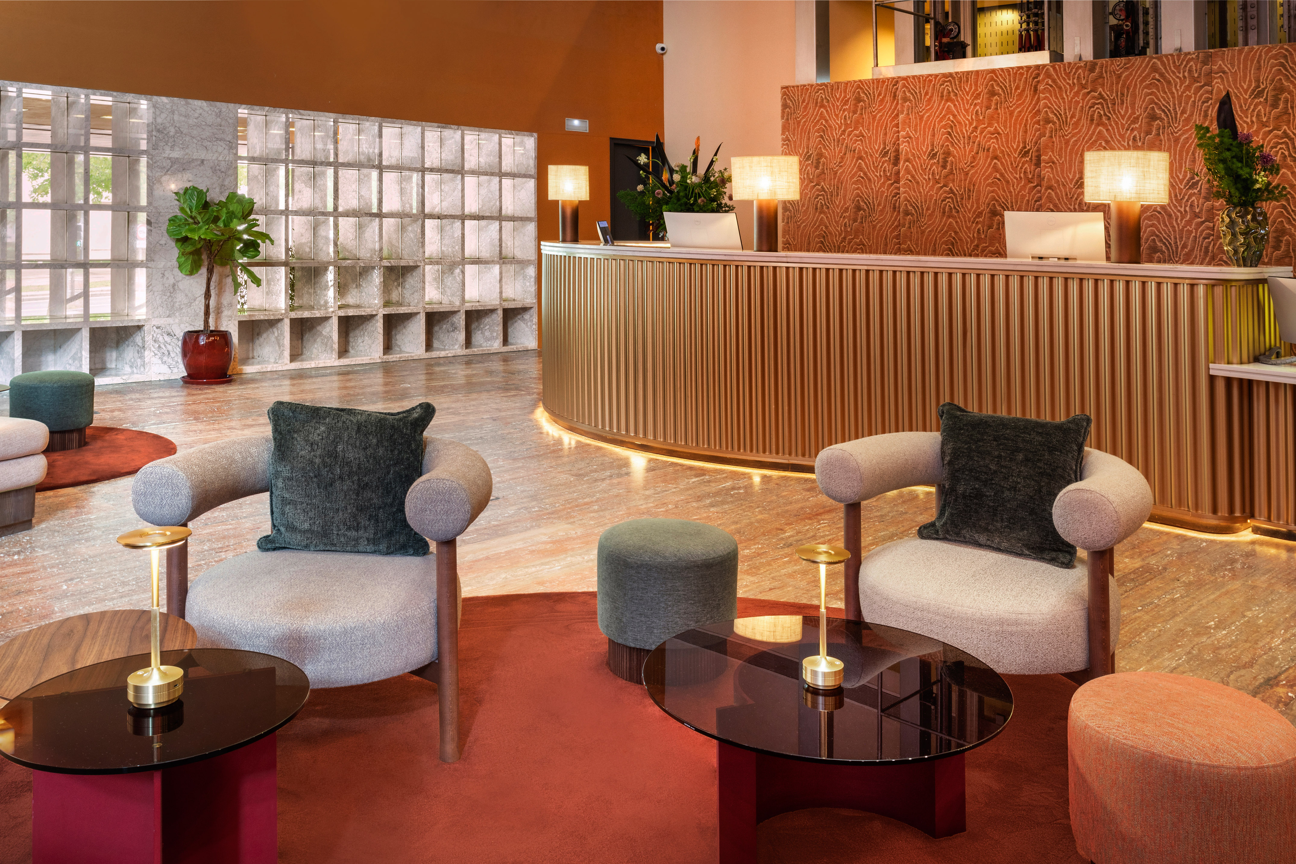 Modern hotel lobby with golden reception desk, plush seating, and warm lighting.